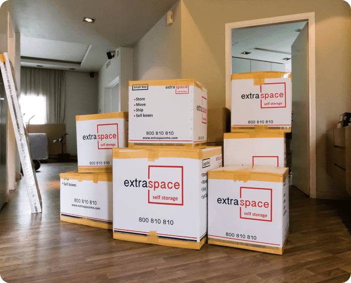 Several stacked boxes labeled "Extra Space Self Storage" in a room with wooden flooring, suggesting organisation and readiness for moving or storage.