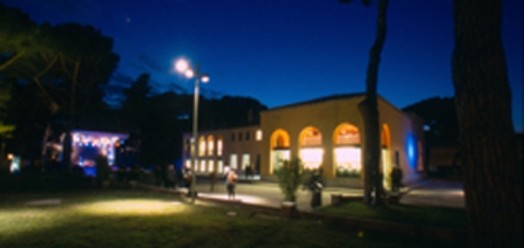 A night photo of an illuminated building with arches.