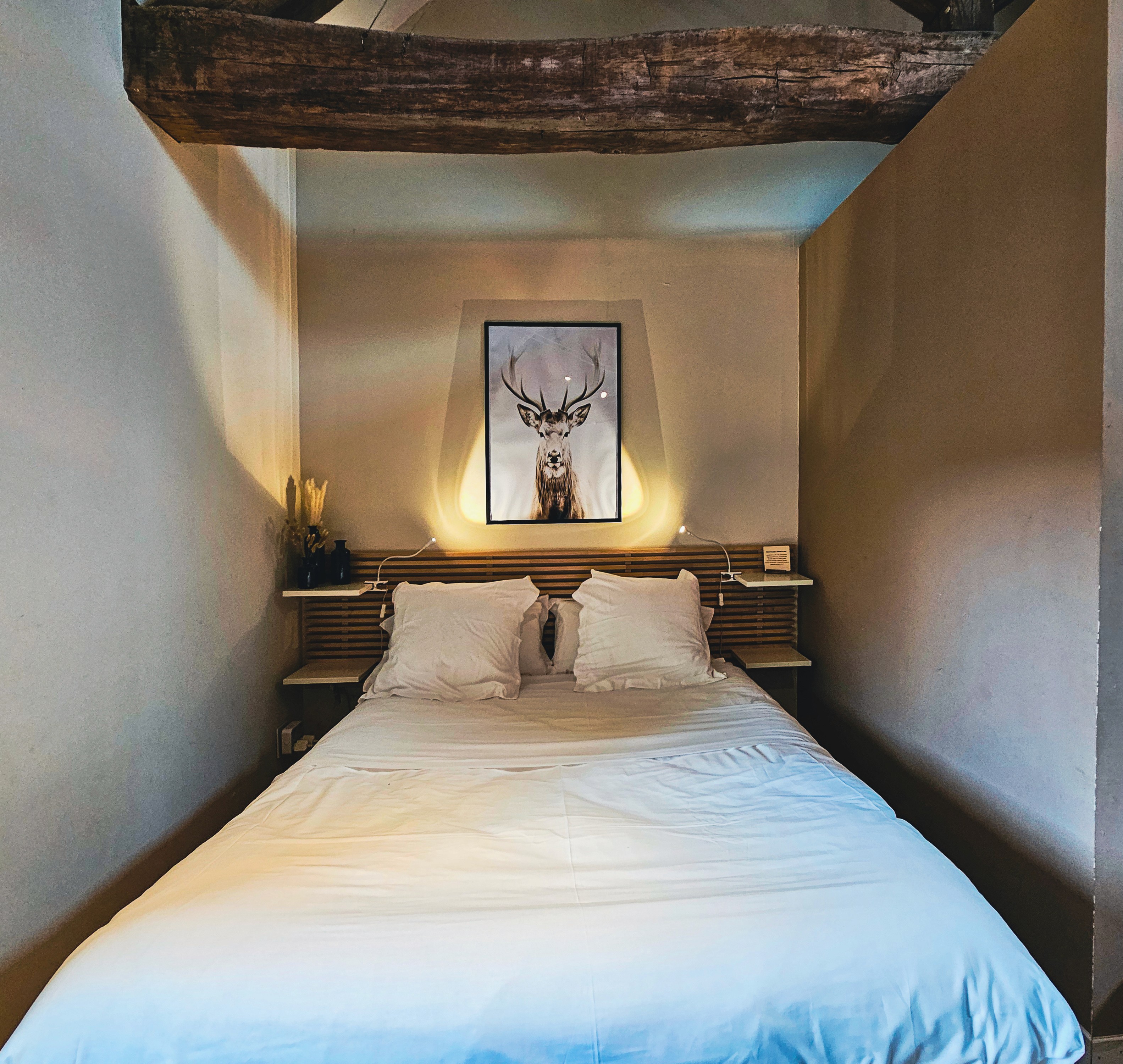 Chambre lit blanc et décoration cerf. Design intérieur moderne et cosy.