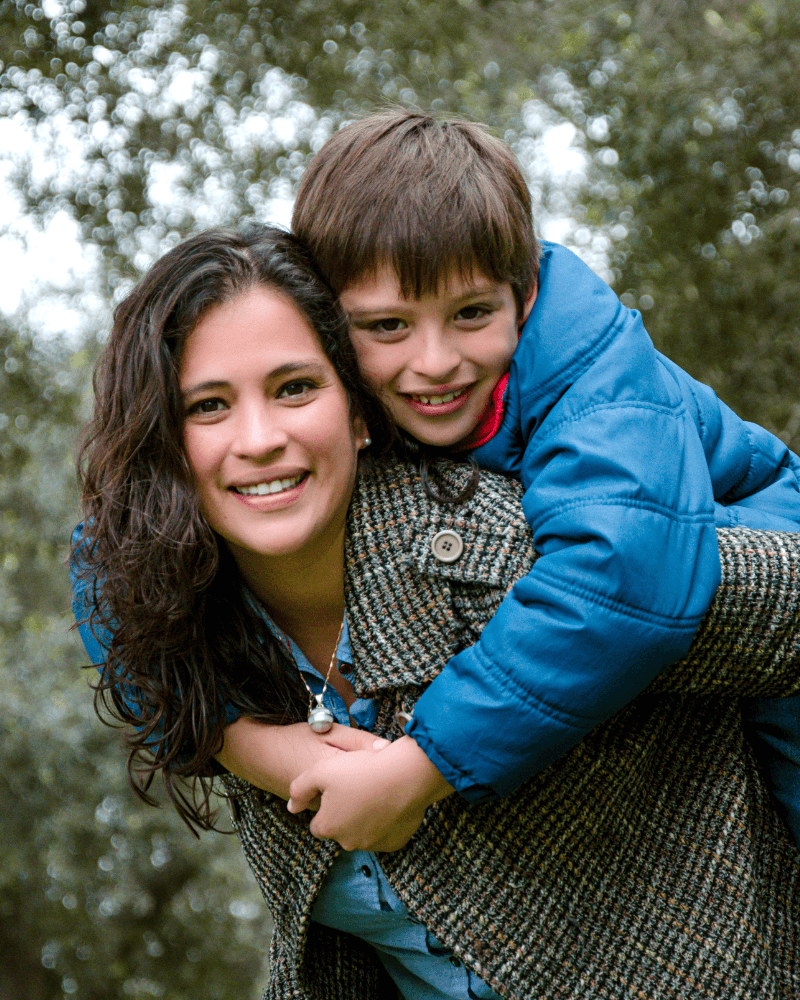 Mother giving her son a piggyback ride in the park, promoting family focus