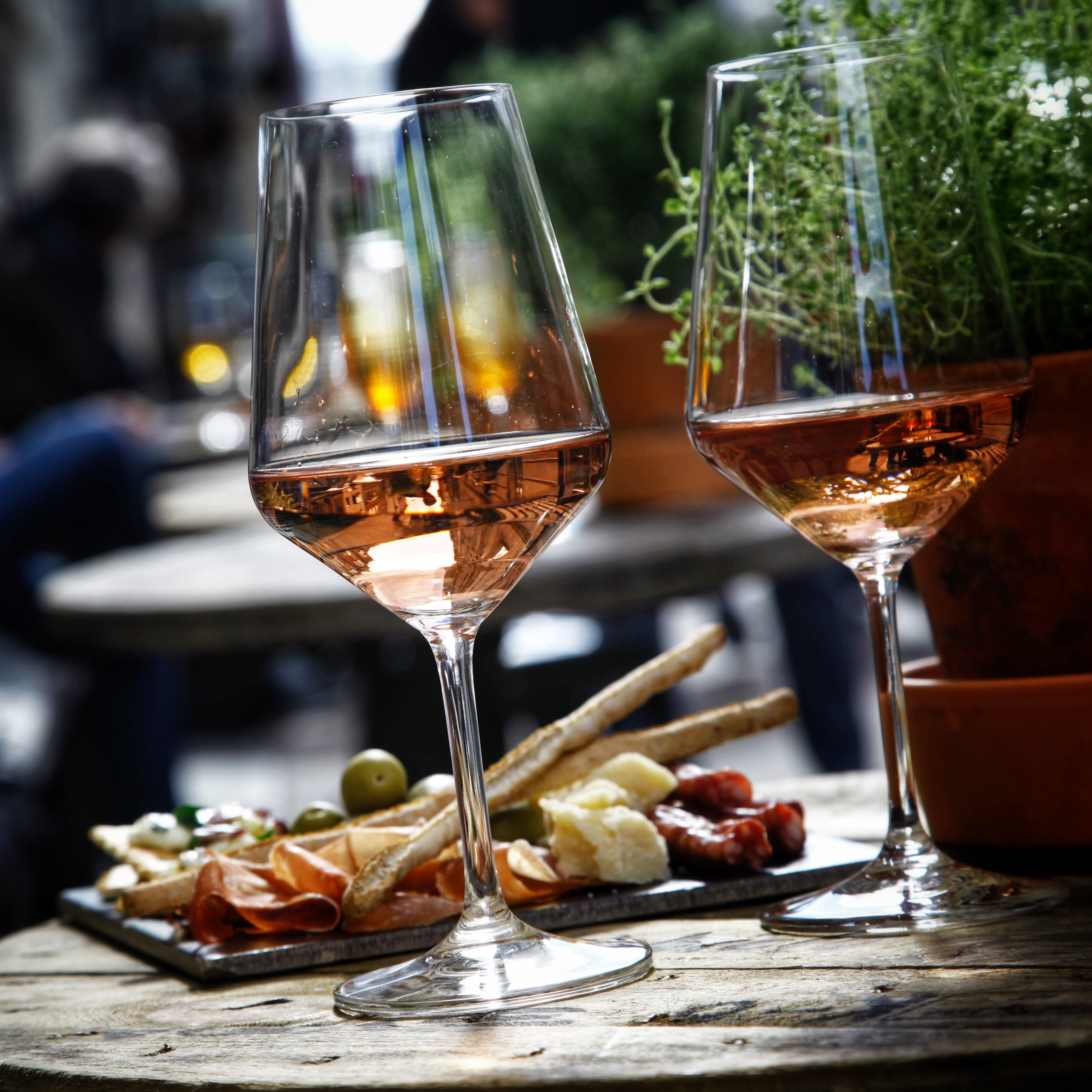 Two glasses of rosé alongside a charcuterie board on a table