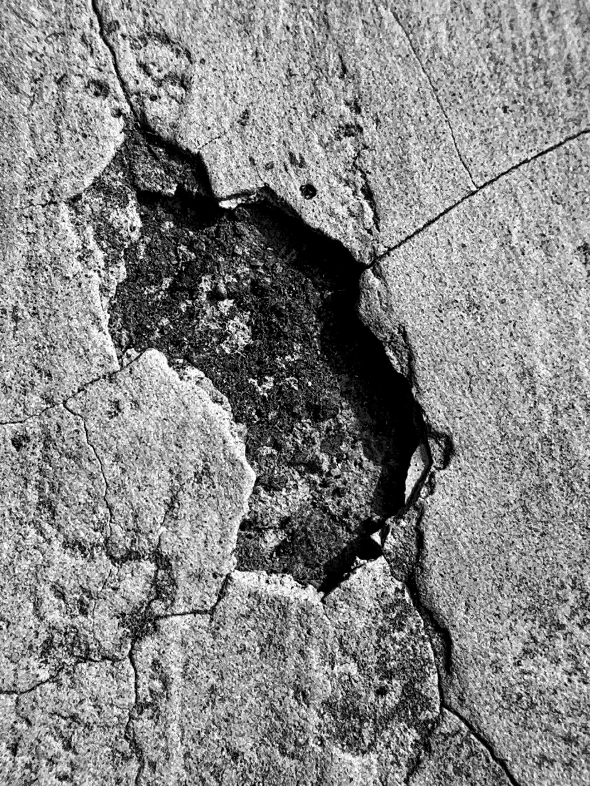 Fissure profonde dans une dalle de béton endommagée.