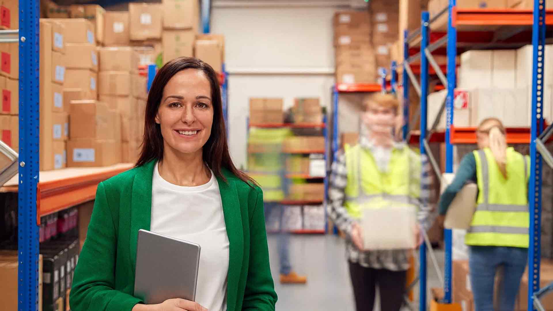 Жінка у зеленому піджаку з планшетом на складі логістичної компанії ASR Logistic