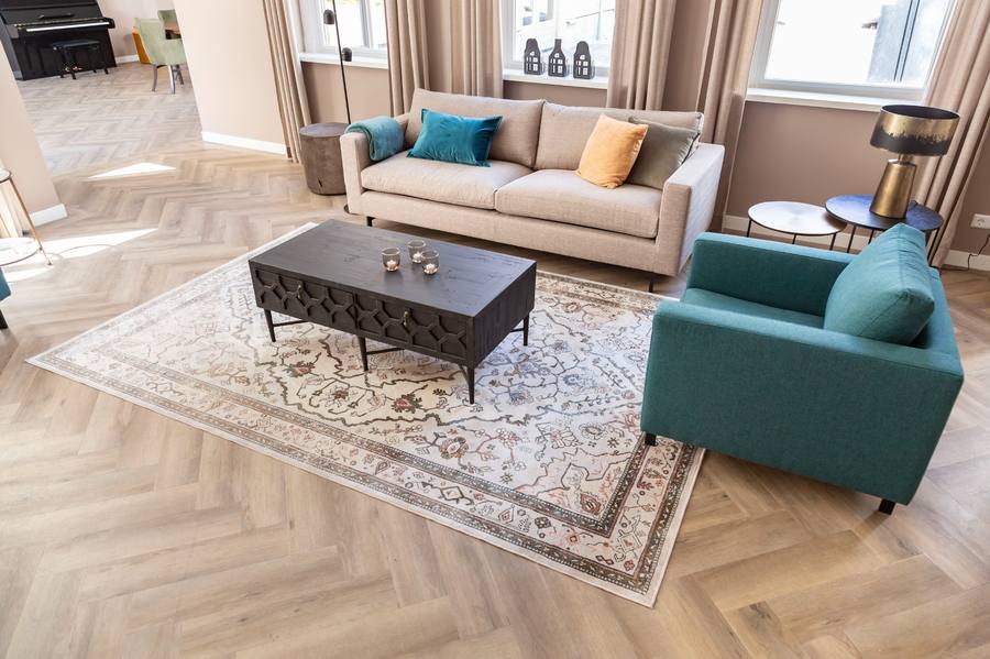 woonkamer lichte bank en blauwe fauteuil met vintage vloerkleed