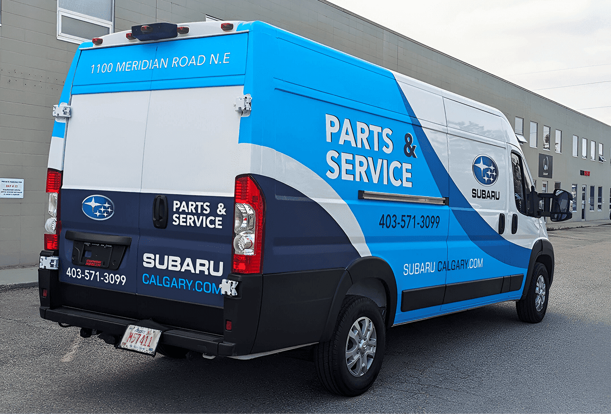 dodge windowless white van with white and blue vinyl graphics for Subaru, back-right view