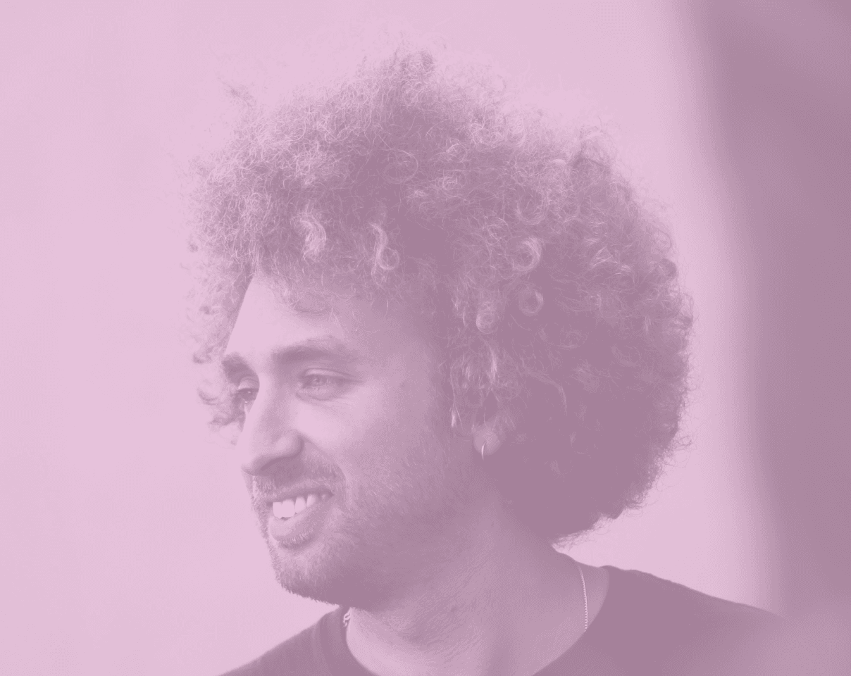 A close-up of a pink cocktail in a martini glass, set against a nighttime background with soft, blurred colors.