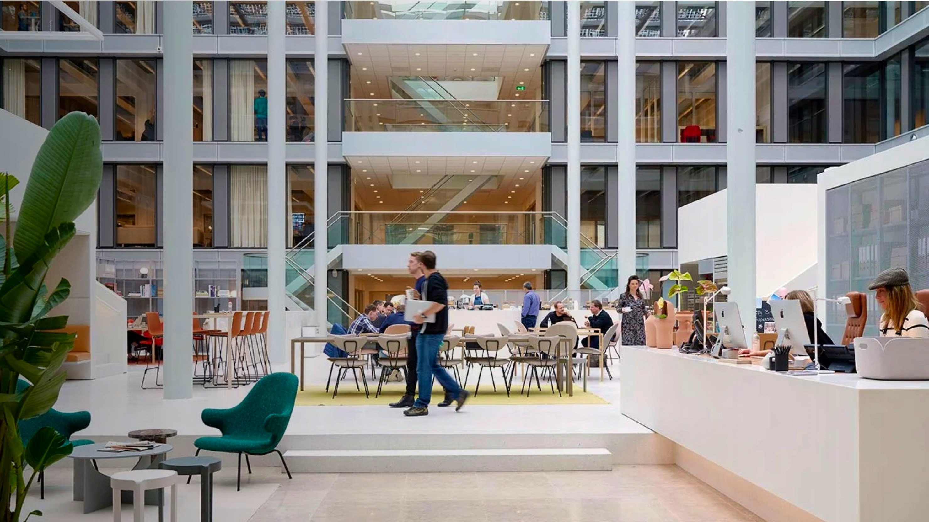 Spaces — interior of a modern multi-floor coworking office atrium with people working at open tables — Soda Studio case study