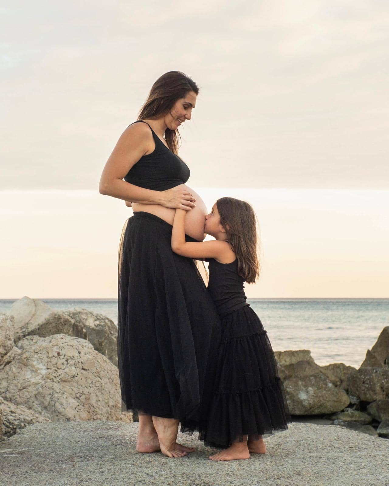 Photo d’un shooting de grossesse : une femme enceinte pose avec sa fille, une idée de cadeau souvenir pour future maman.