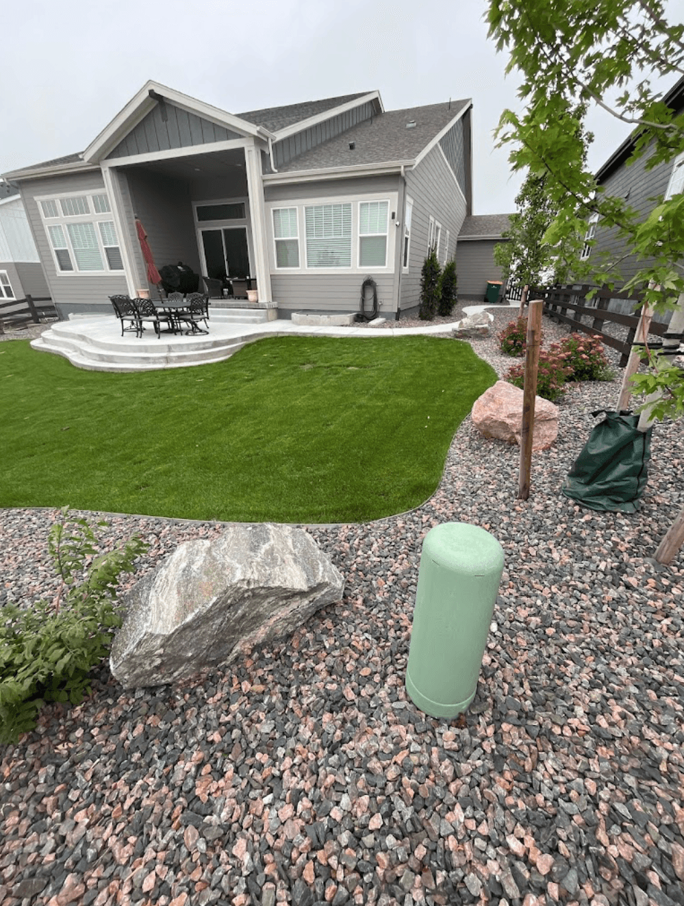 artificial grass installation in the backyard with stones and boulders around it