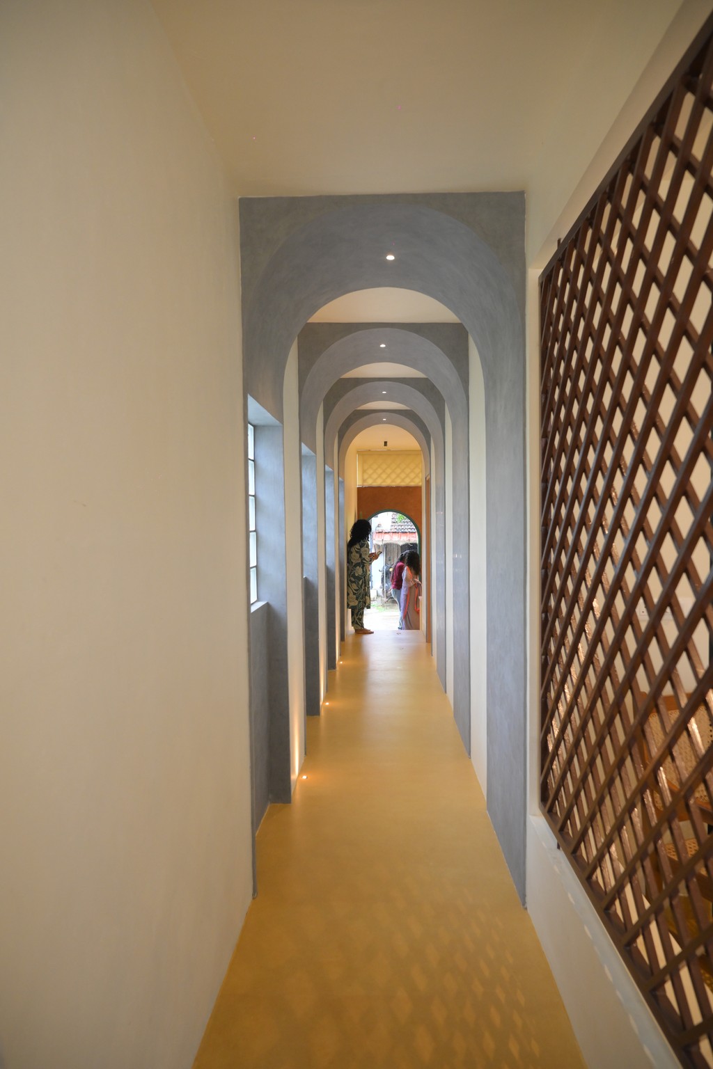 A woman with a white headband relaxing, her face illuminated by warm sunlight filtering through blinds, casting striped shadows. She has a serene and peaceful expression.