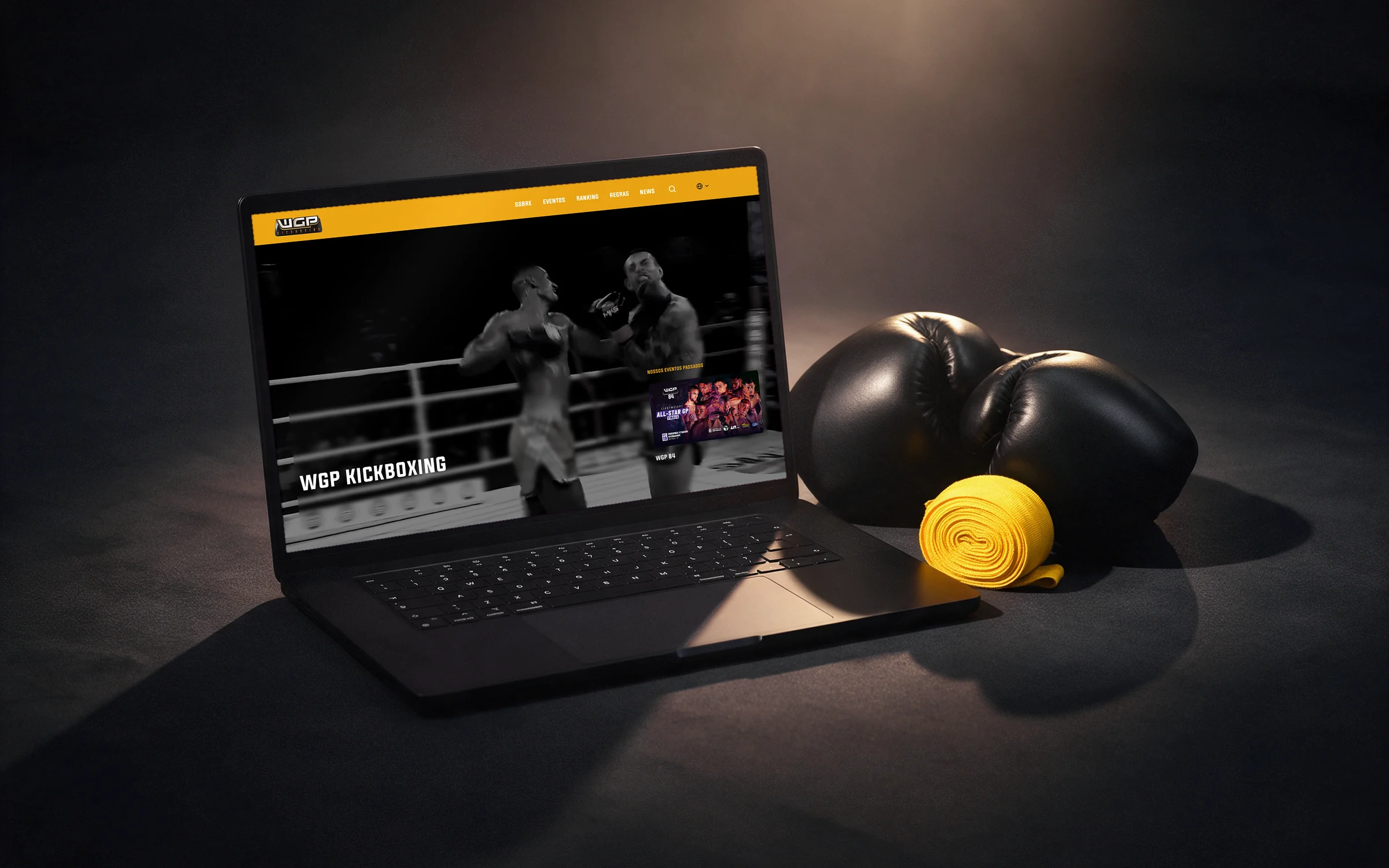 Página inicial do site do WGP Kickboxing num notebook, ao lado de luvas de boxe