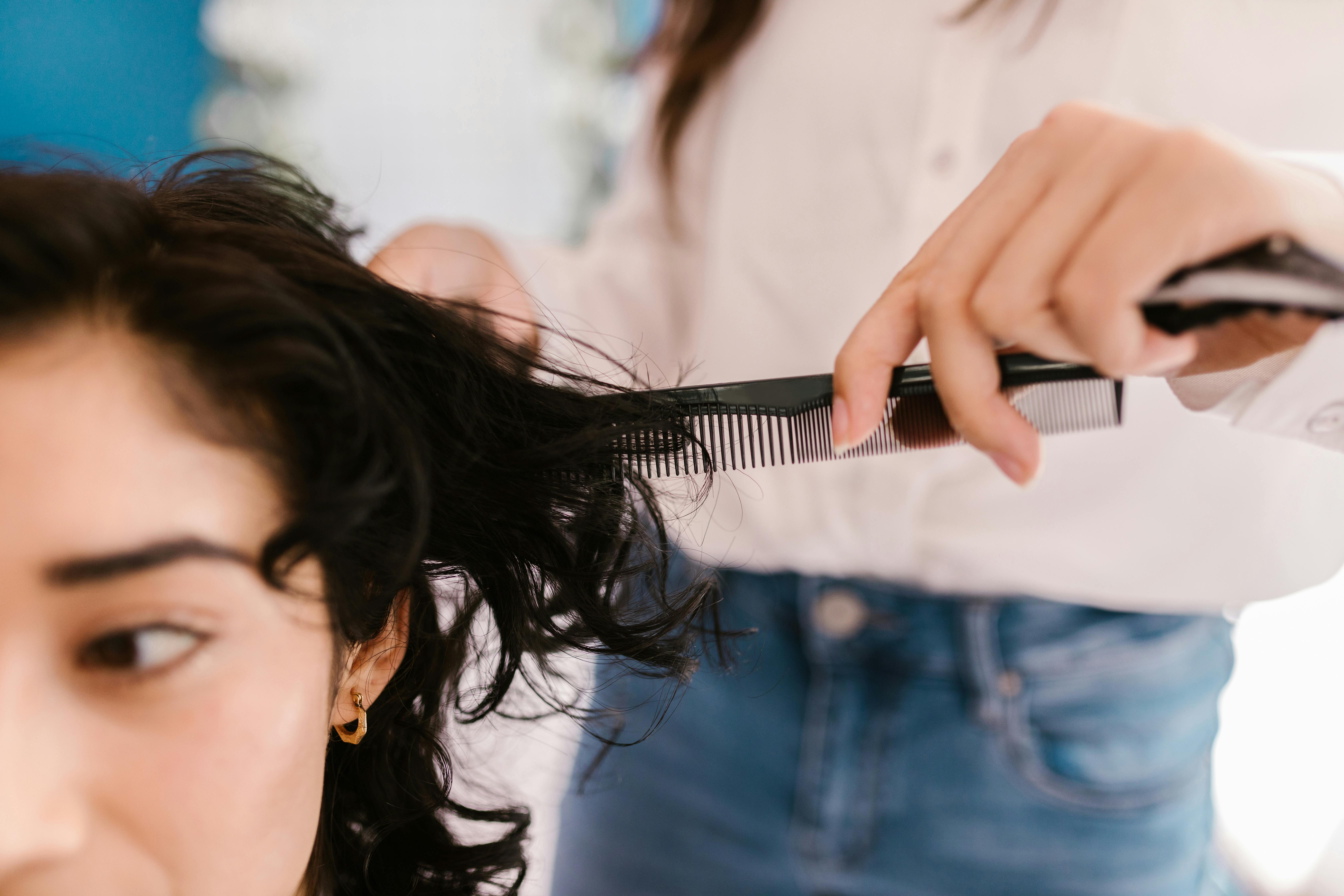 Woman with mid-length black hair getting their hair cut at hair salon