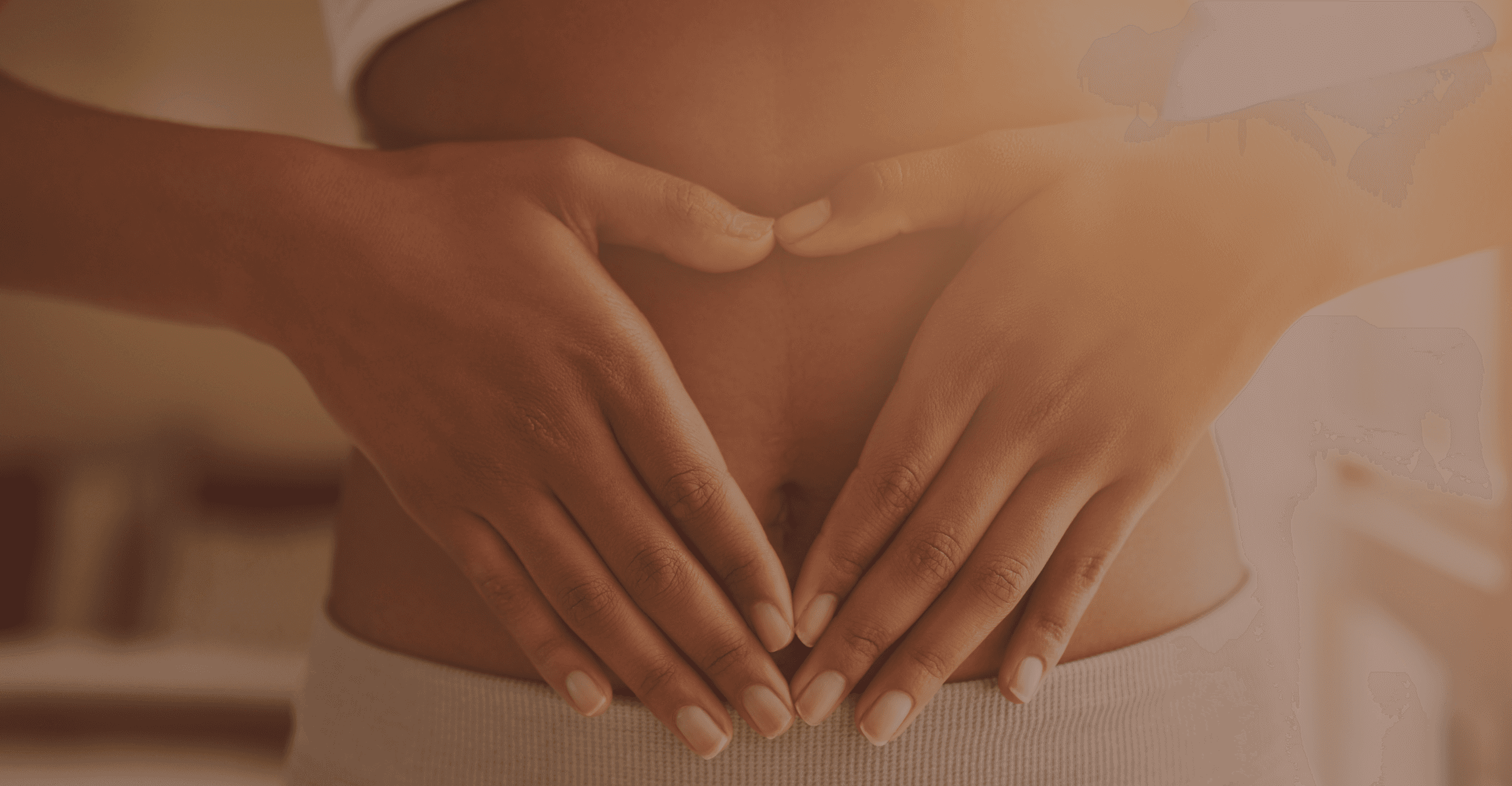 A woman with her hands in a heart shape placed on her stomach, wearing white clothing, up close to her stomach.