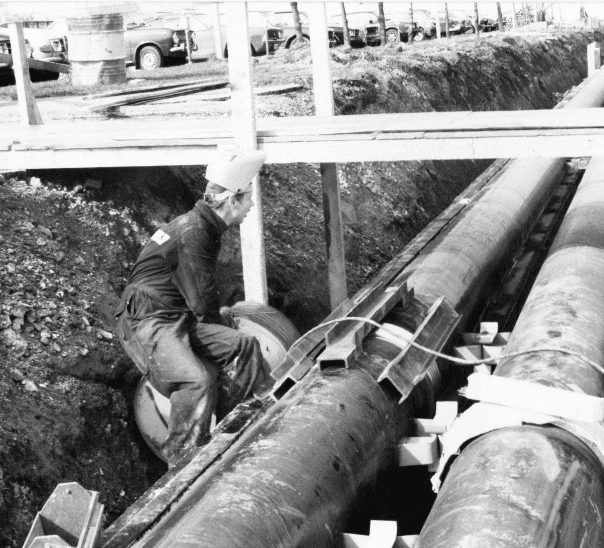 Old photo of person standing on top of district heating pipe