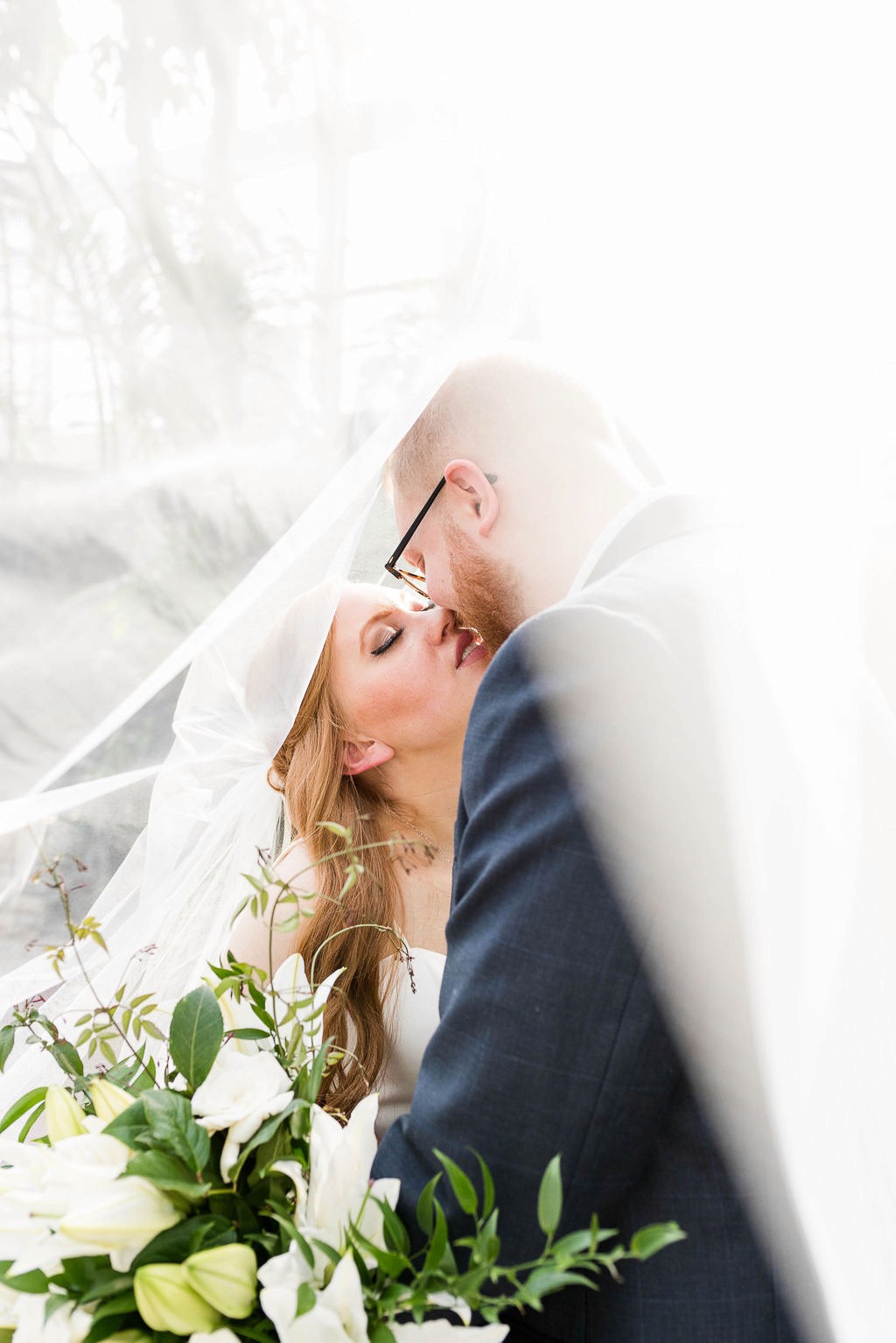 Bride and groom kissing under veil with bridal bouquet in Nashville Tennessee.