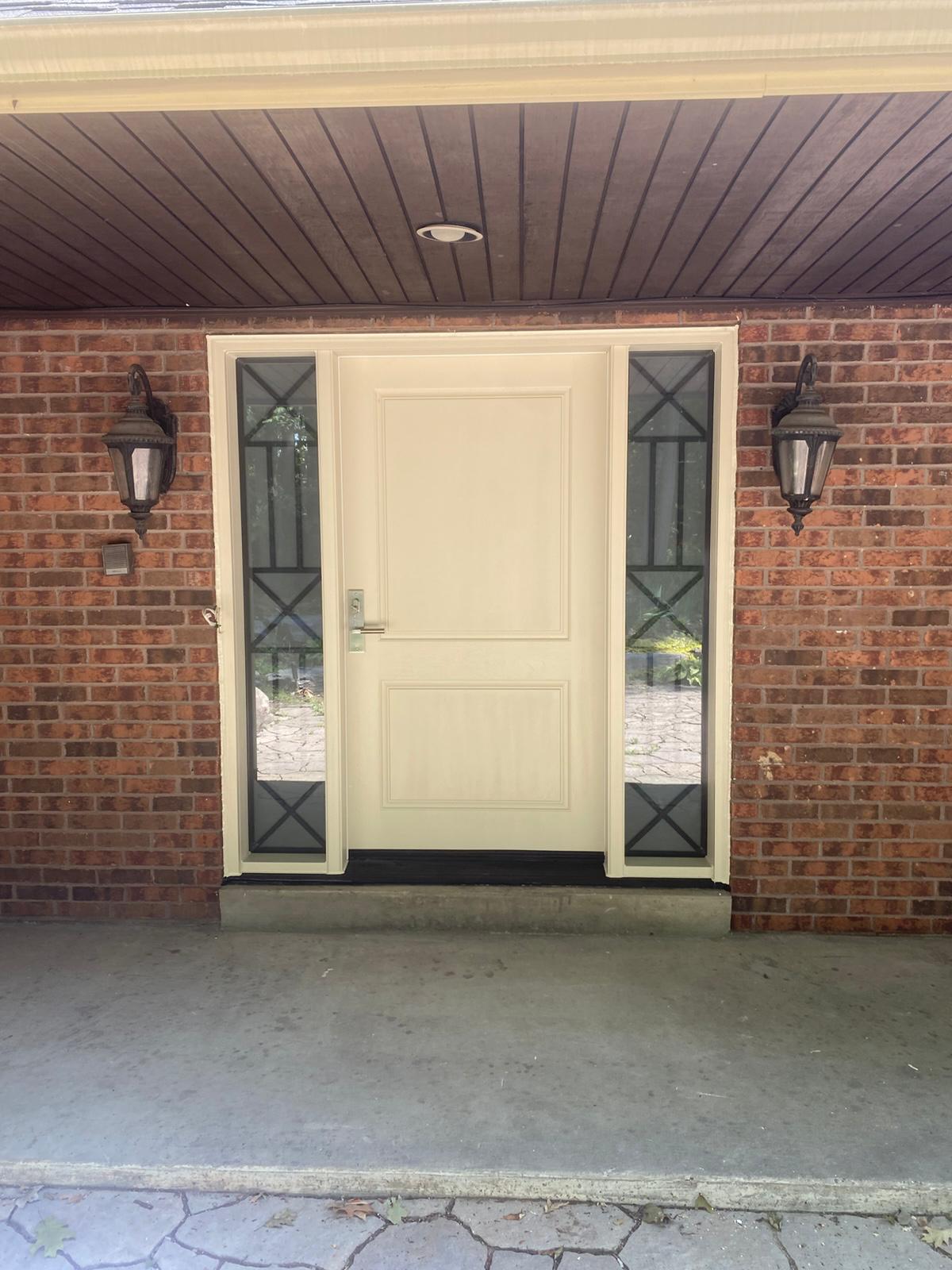 Cream steel front door with two decorative iron glass sidelites on a red brick Ontario home
