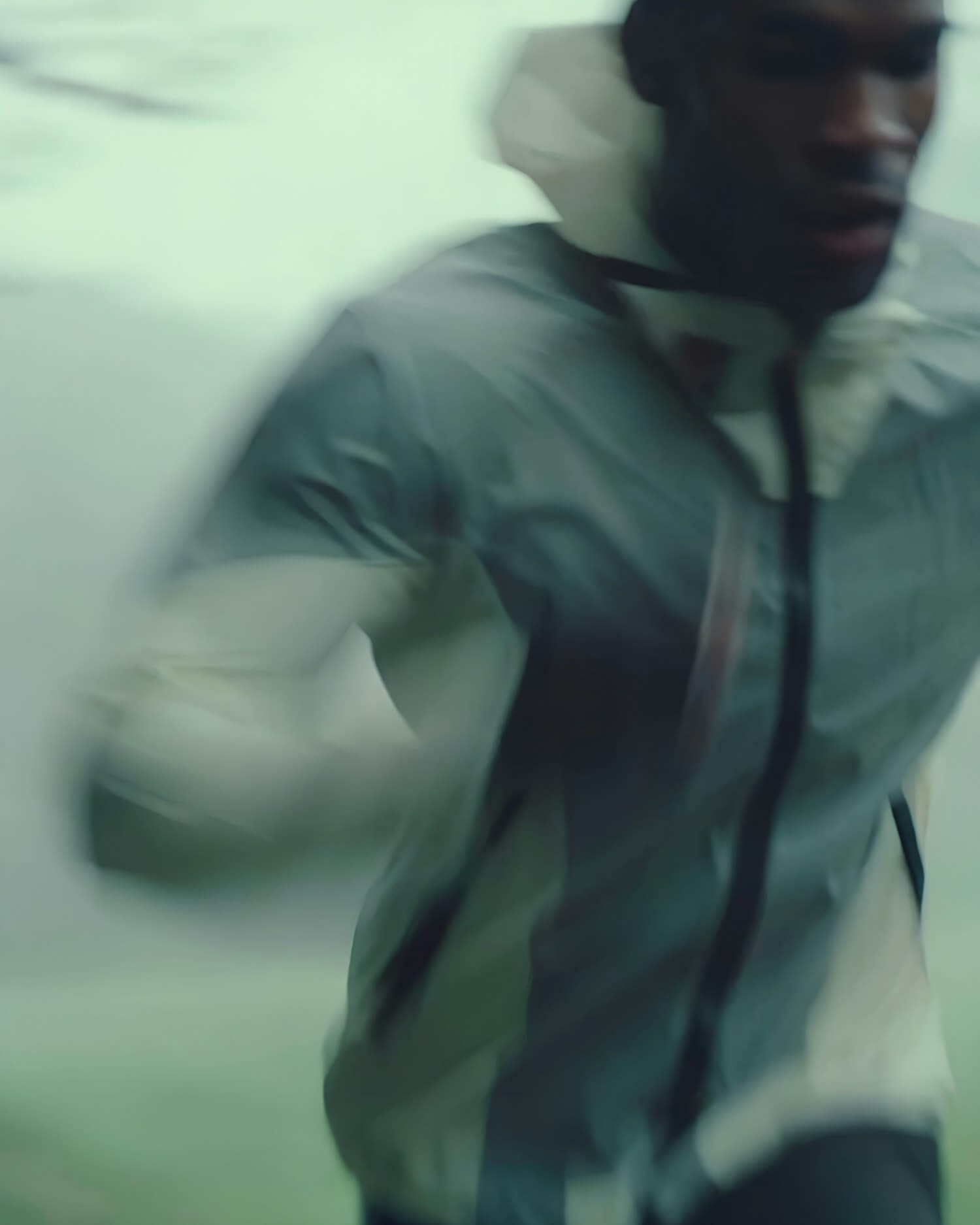 Runner in a hooded jacket sprinting with motion blur
