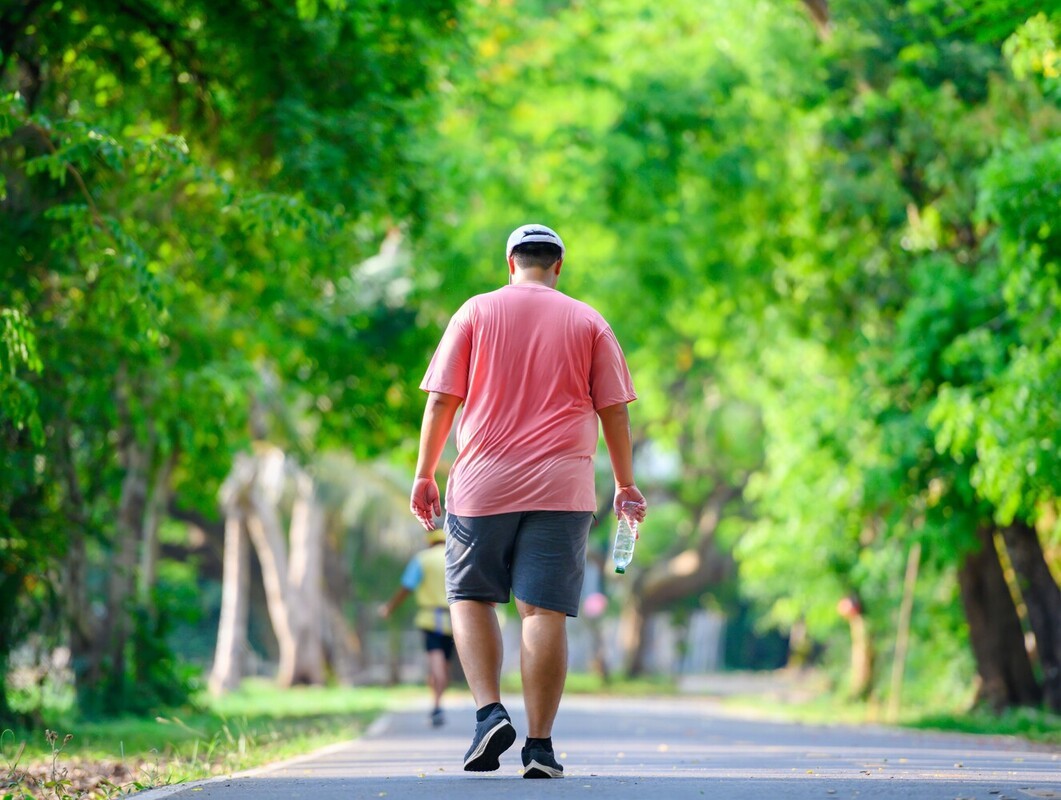 overweight man sweating while he follows a longer route outside as he learns how to walk to lose weight more effectively
