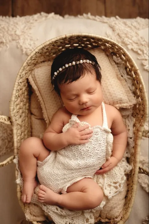 Newborn with a headband in a wicker basket