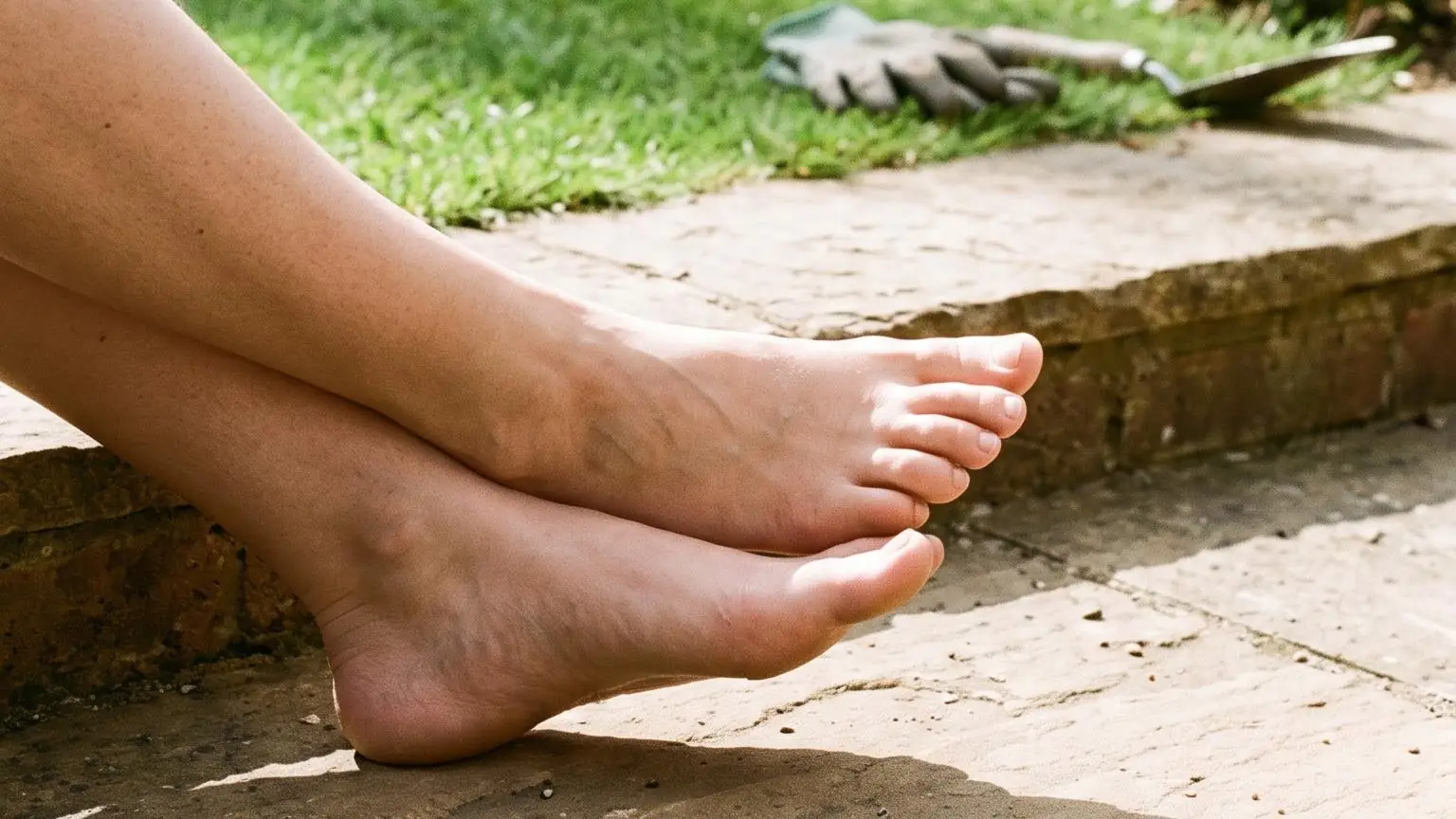 Bare feet resting on a warm stone garden step in bright early morning sun