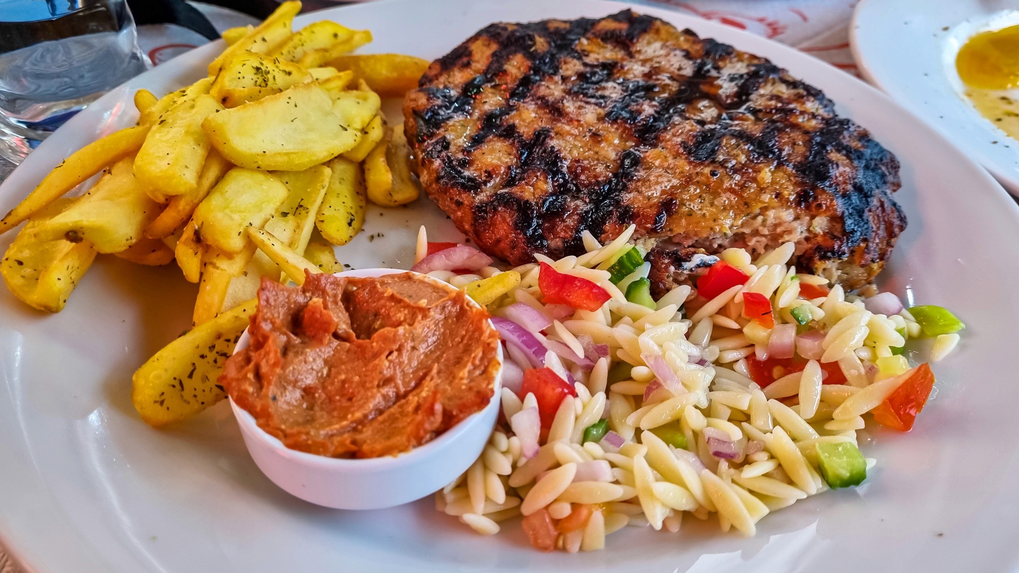 Greek burgers (biftekia) served with red sauce, fried potatoes and salad