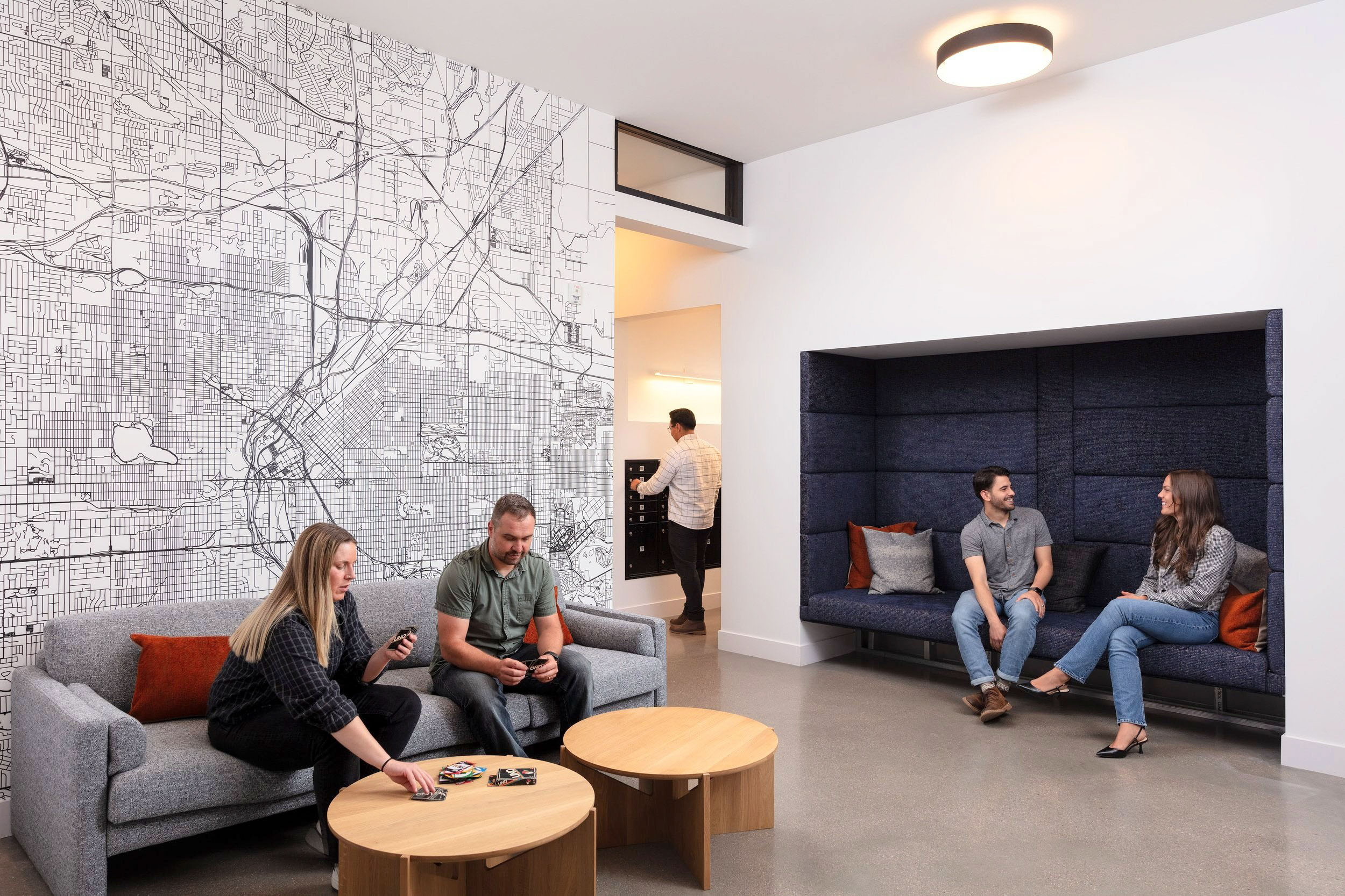 People in a modern lounge area with city map wallpaper.