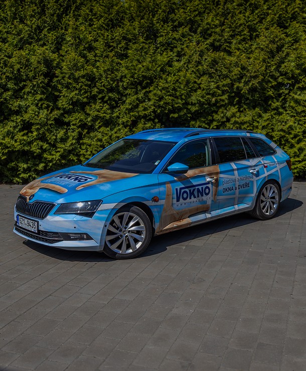 Zaparkovaný stříbrný firemní vůz s brandingem Vokno