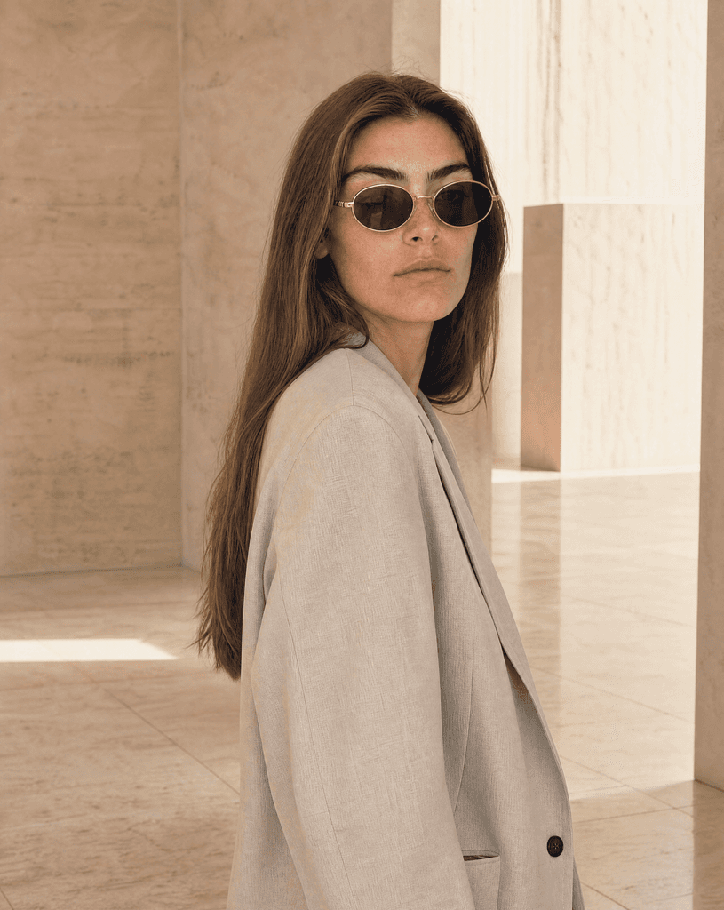 The recurring Riviera hero model wearing black sunglasses beside pale limestone overlooking the coast.
