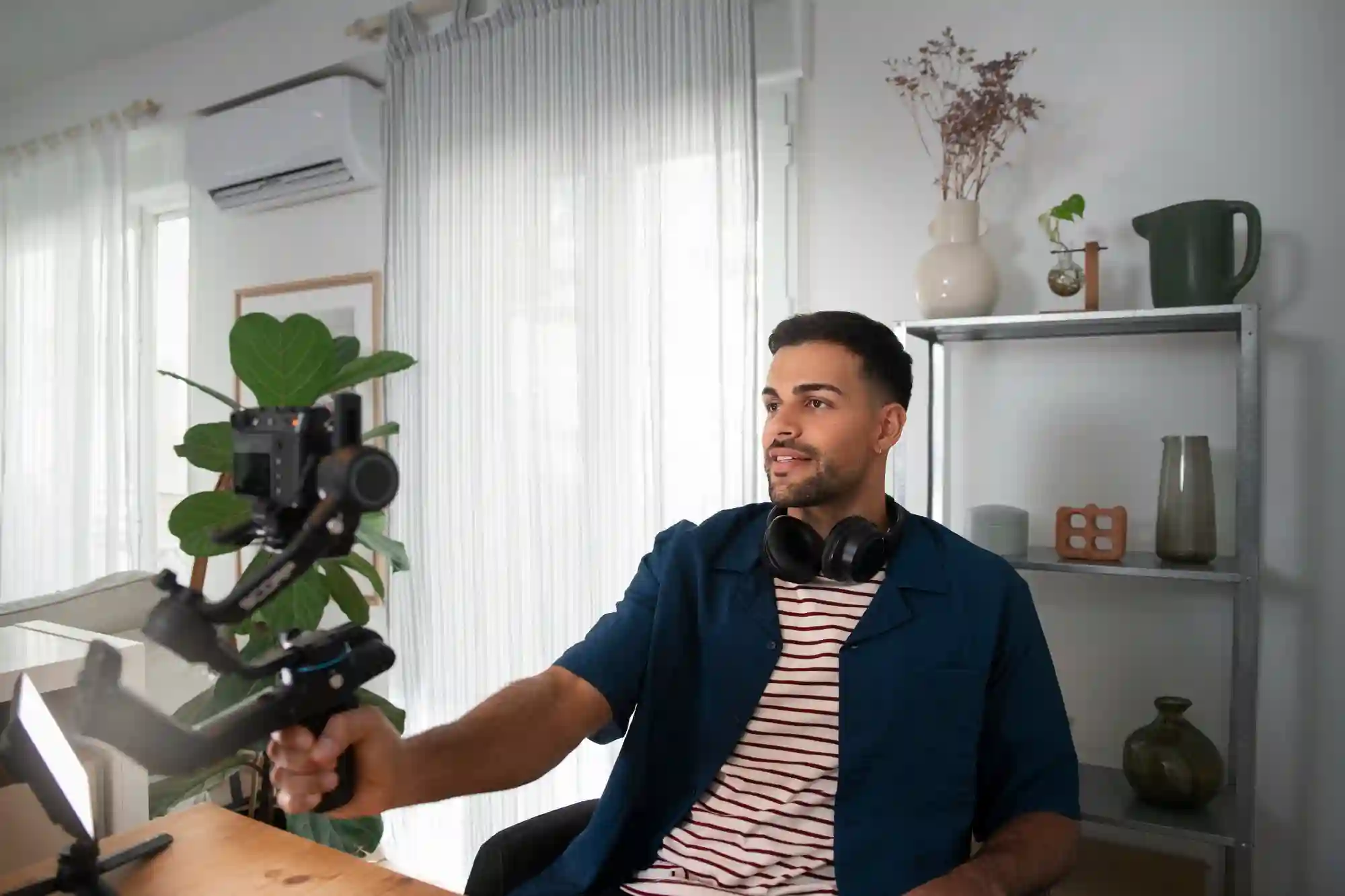 A young male content creator using a camera stabilizer to film high-quality video content in his modern home.