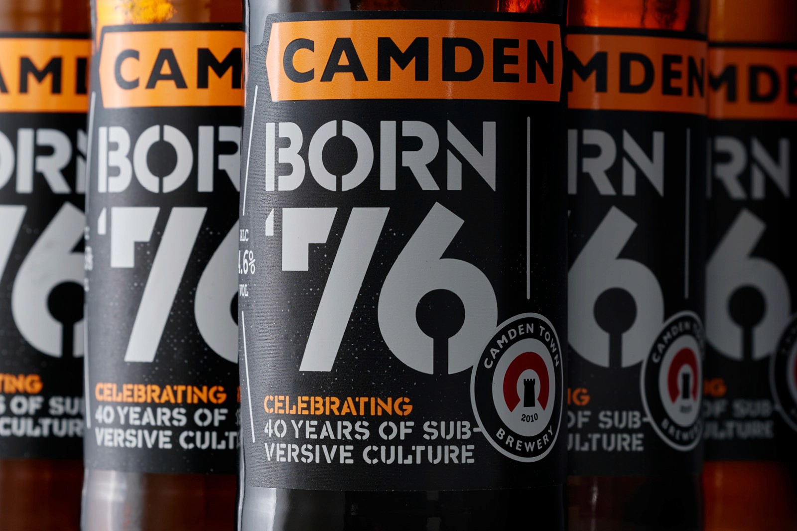 A close-up of beverage cans, featuring bold black labels with the text "BORN 76" and the number "6," stacked together.