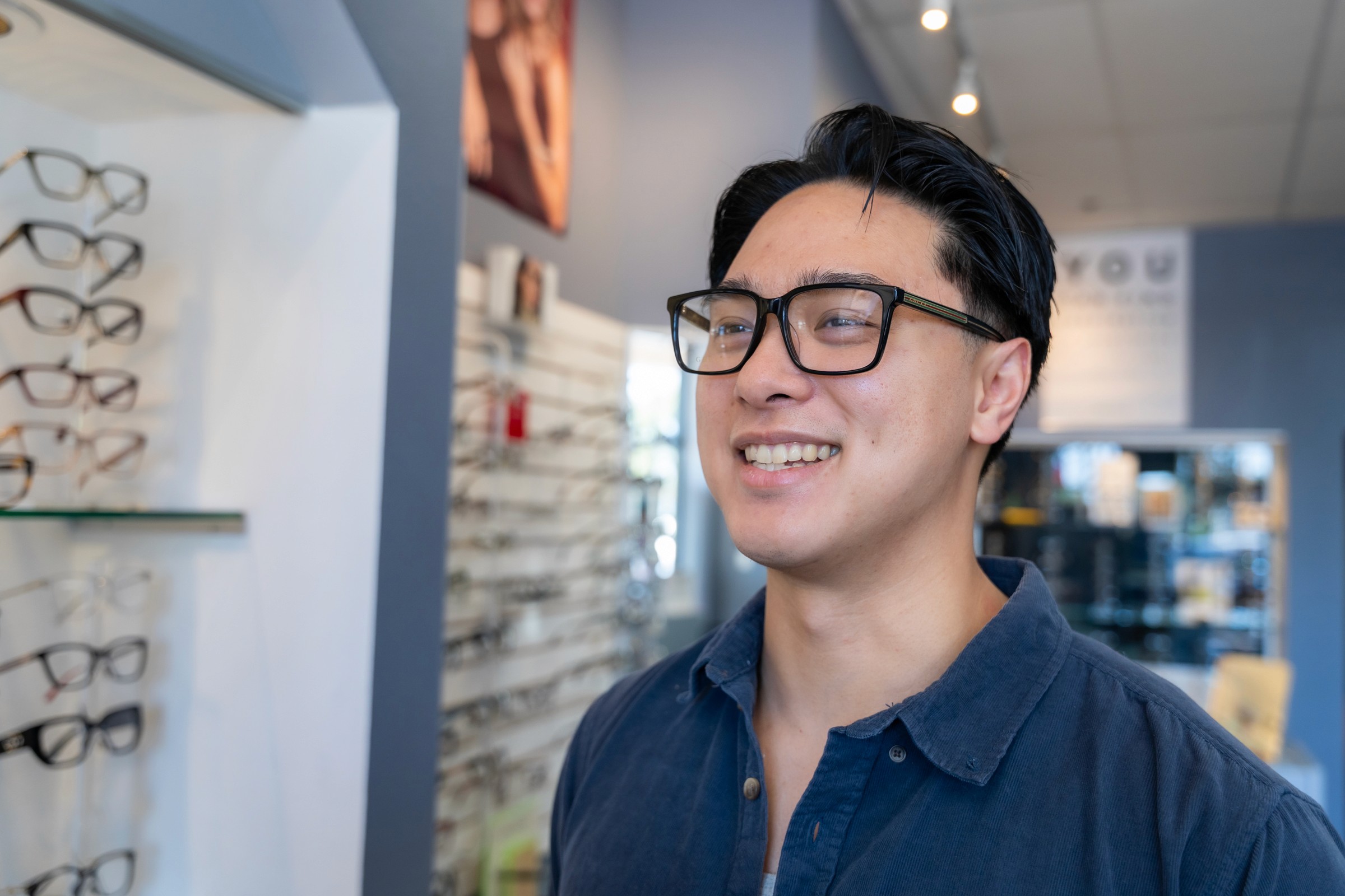 Young man wearing her new glasses at an optometry.