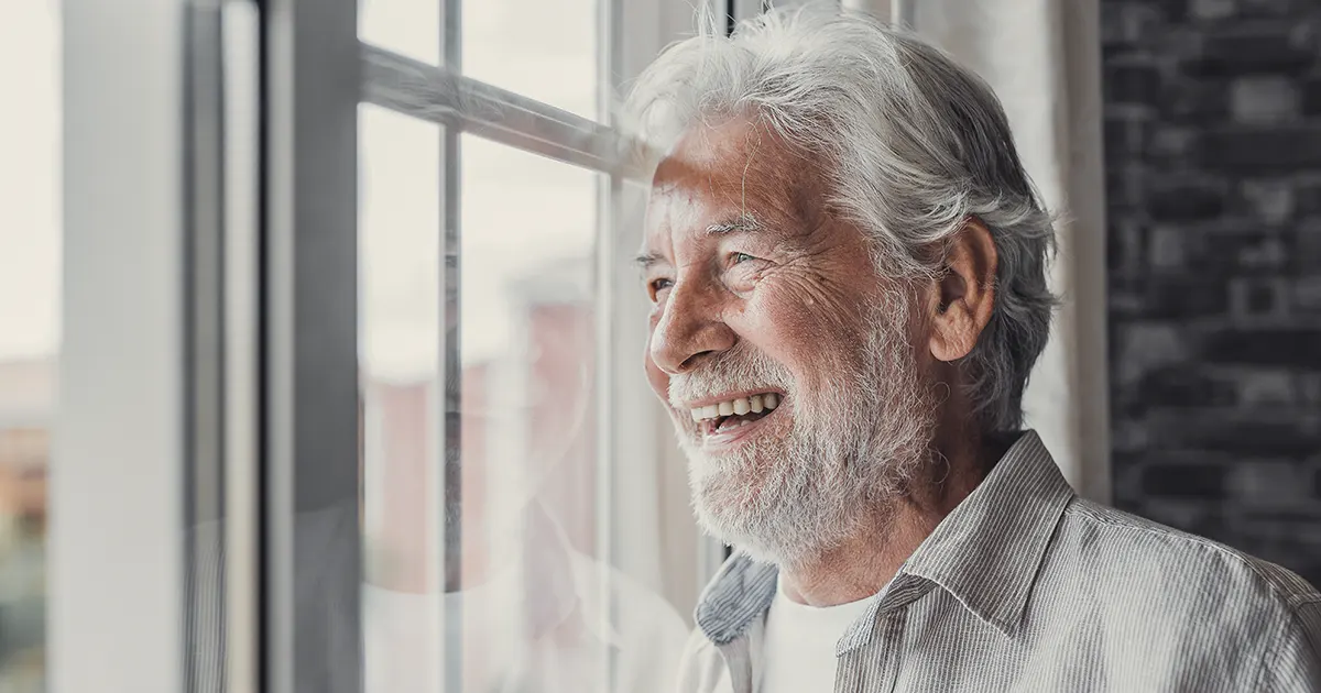 Picture of an elderly man looking out the window.