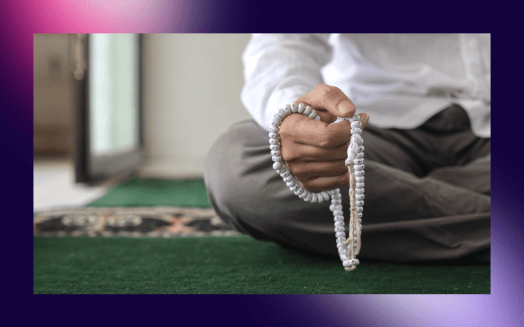 Individual sitting on a prayer mat using prayer beads (tasbih), indicating a moment of dhikr or personal reflection in Islamic practice.