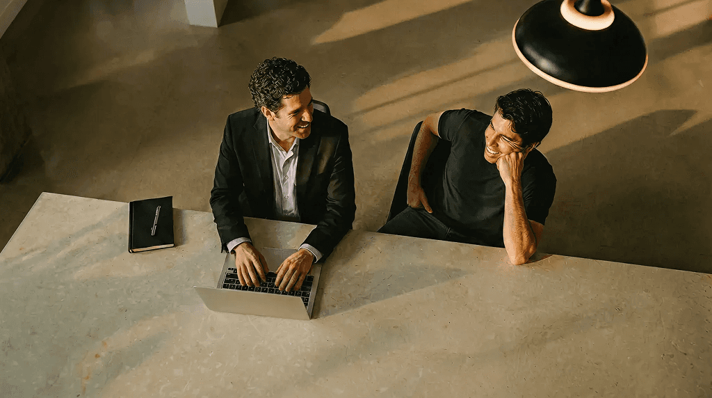 Man and woman working side by side at a desk, both focused on their laptops.