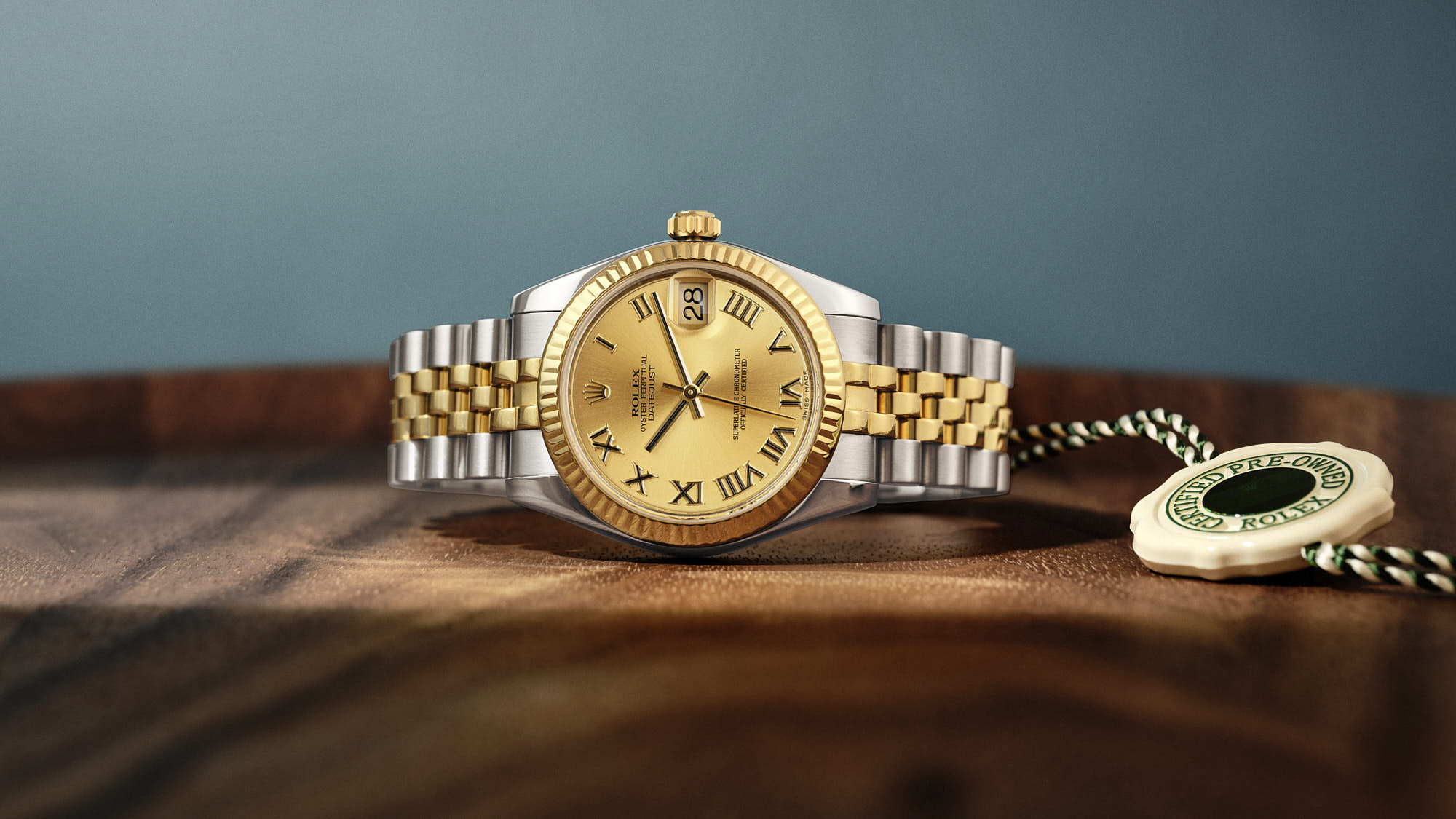 Luxury gold and silver watch on wooden surface with certification tag.