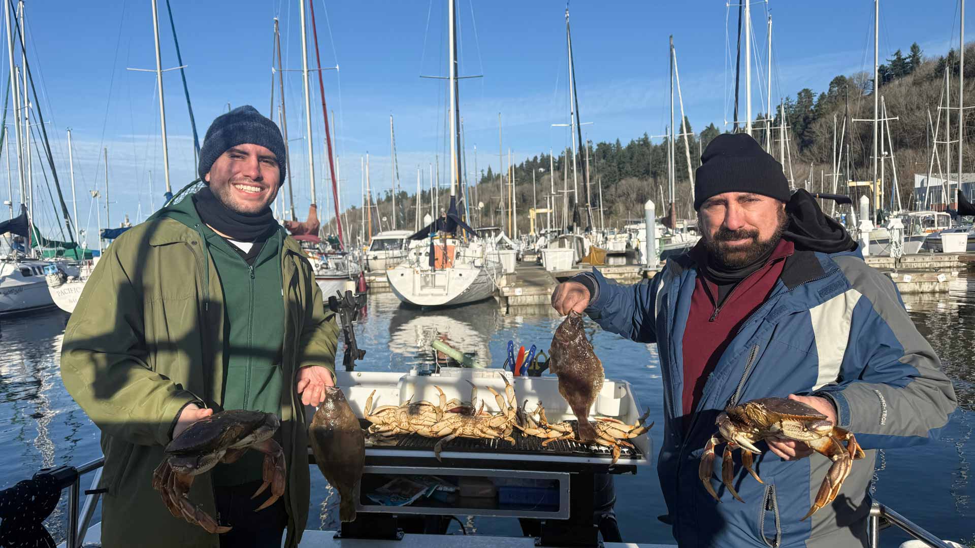 Father and son showing of freshly caught crab and flounder