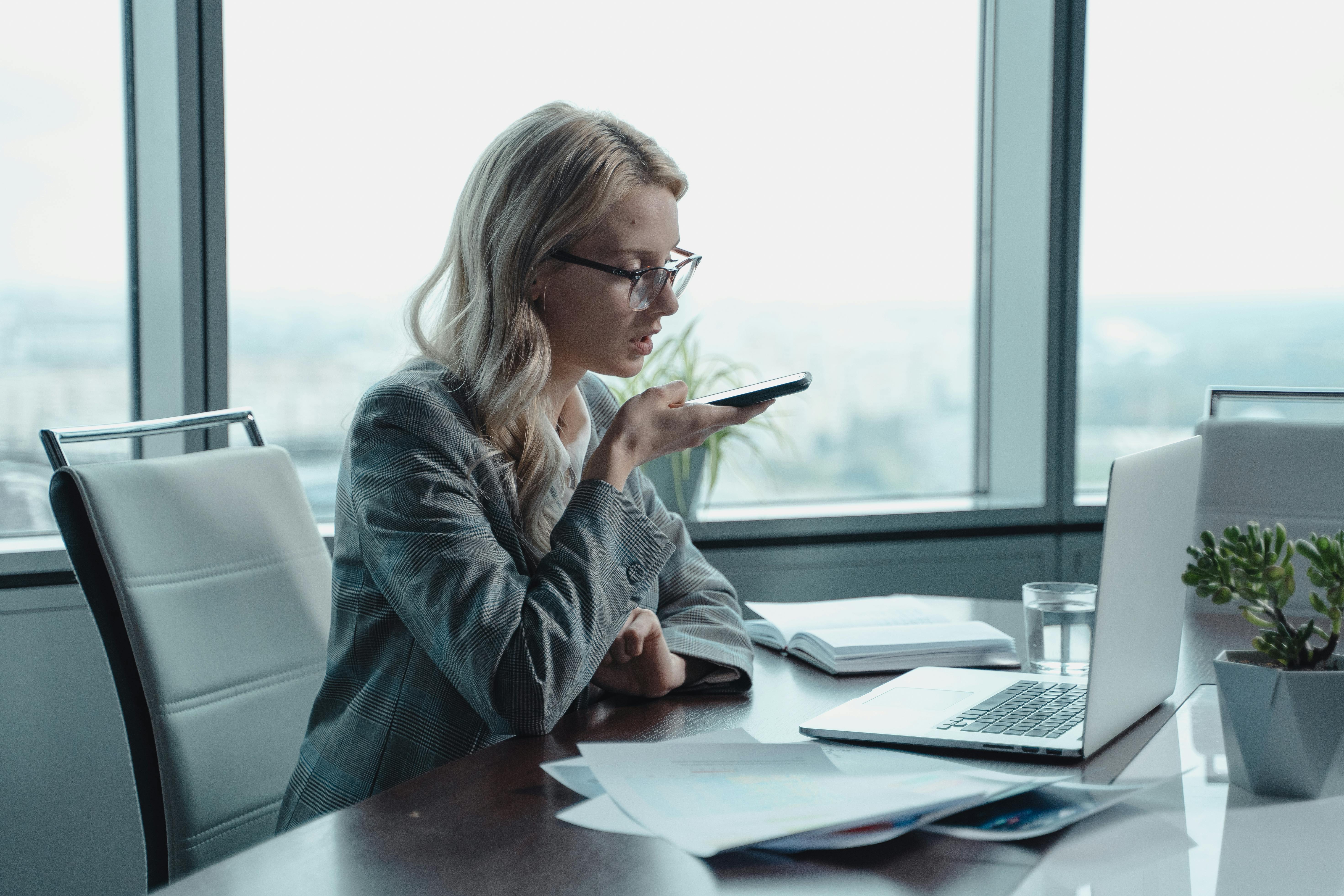 Professionista che utilizza lo smartphone in ufficio mentre lavora al computer, rappresentazione di una strategia attiva di posizionamento professionale e contatto diretto con recruiter e aziende.