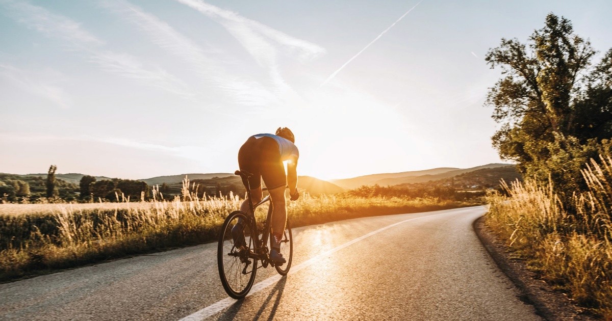 Cyclist riding on an open road at sunrise, symbolizing vitality, endurance, and a commitment to a healthy lifestyle.