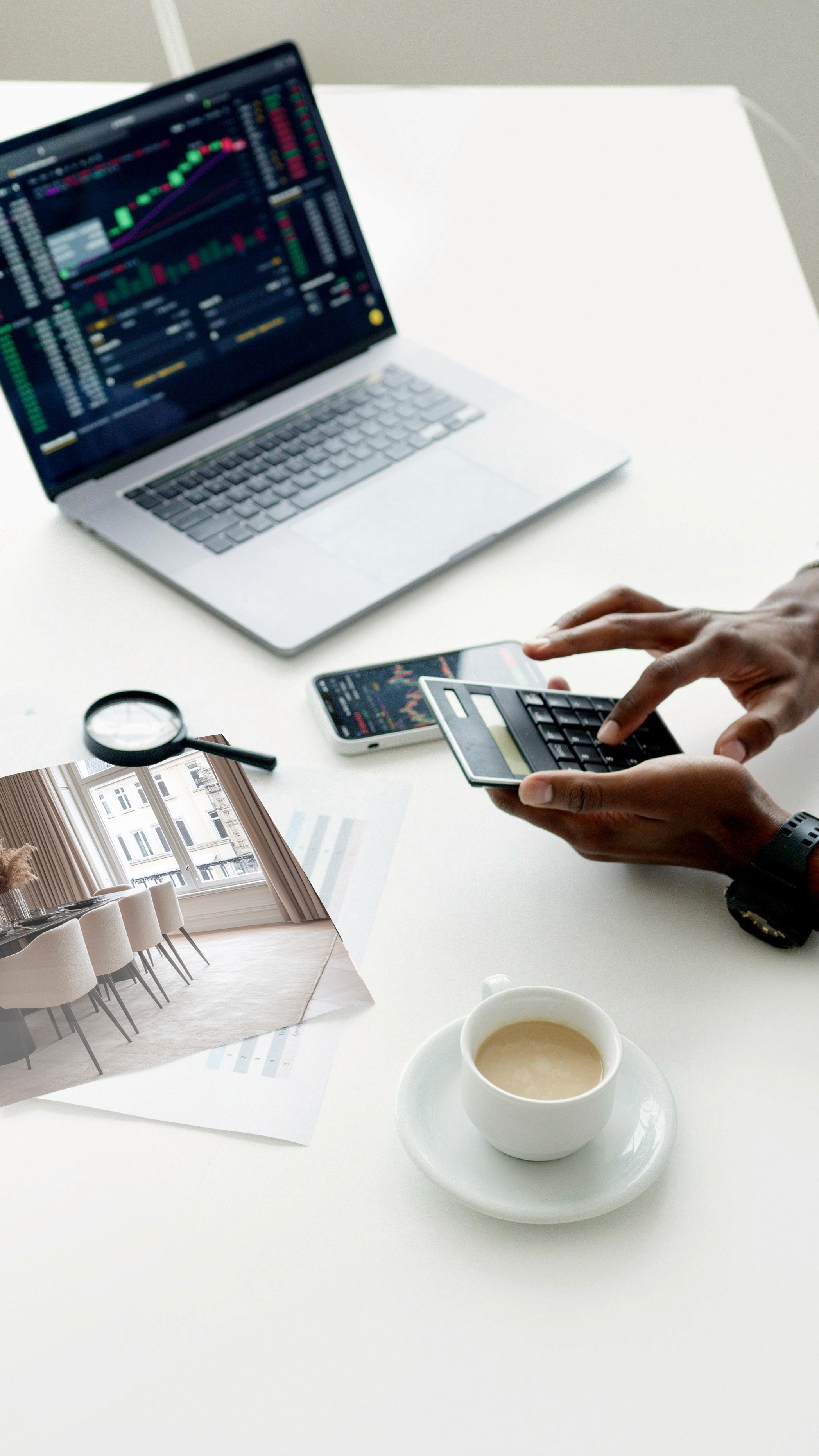 Person nutzt Smartphone an einem Arbeitsplatz mit Laptop, Notizen und Kaffee.