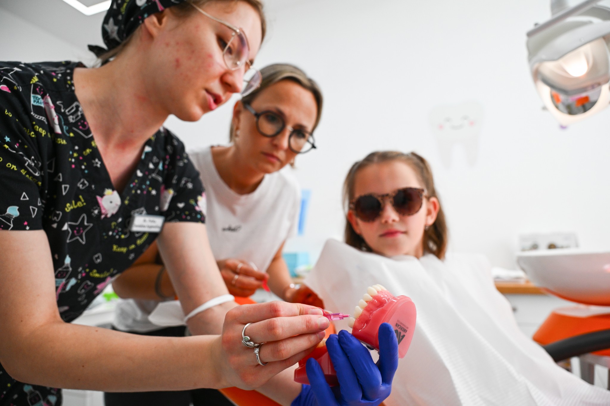 Dentálna hygienička  vysvetluje na modeli čistenie zubov pre mamu  s dieťaťom