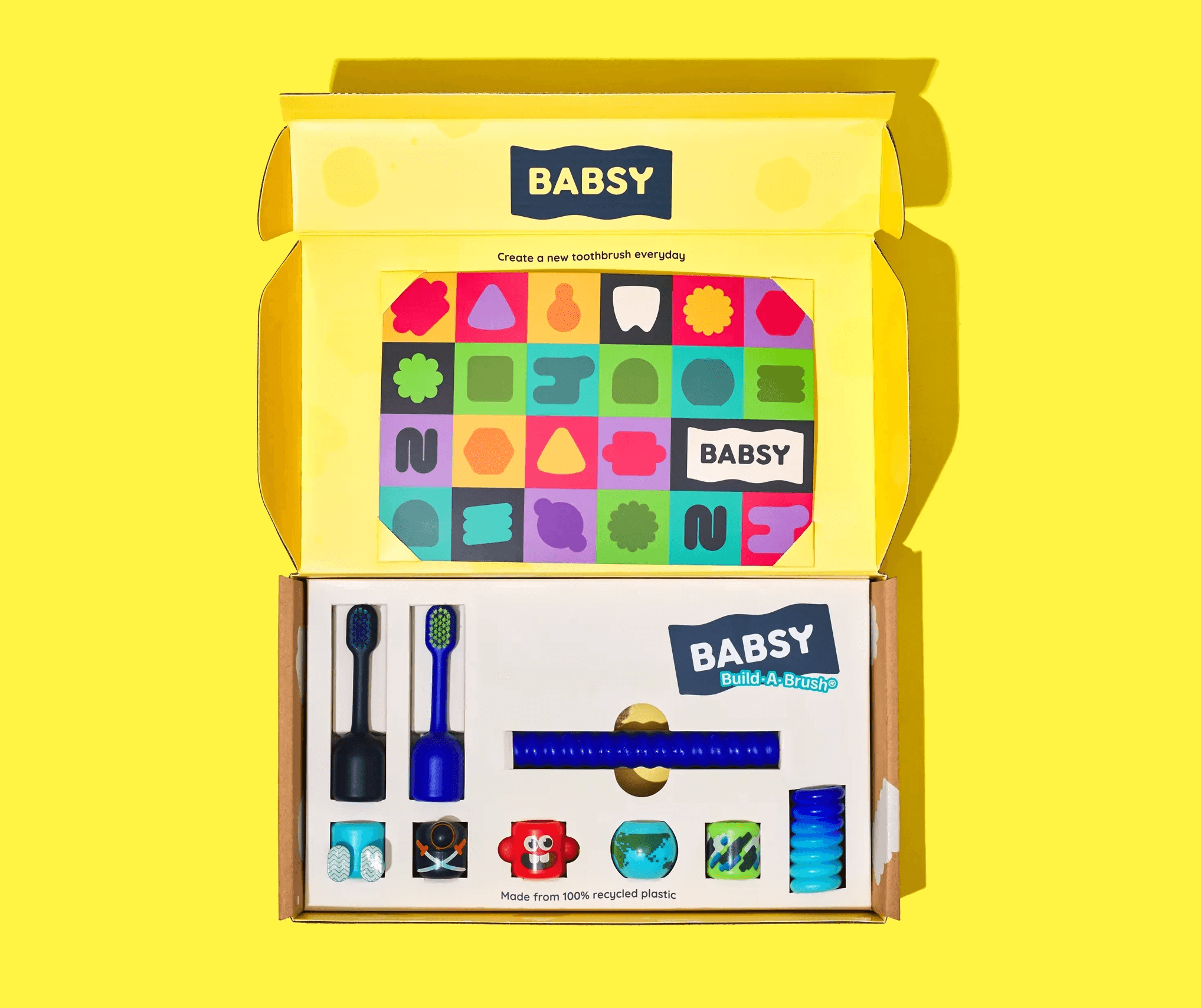 BABSY children's toothbrush packaging kit opened on a yellow background