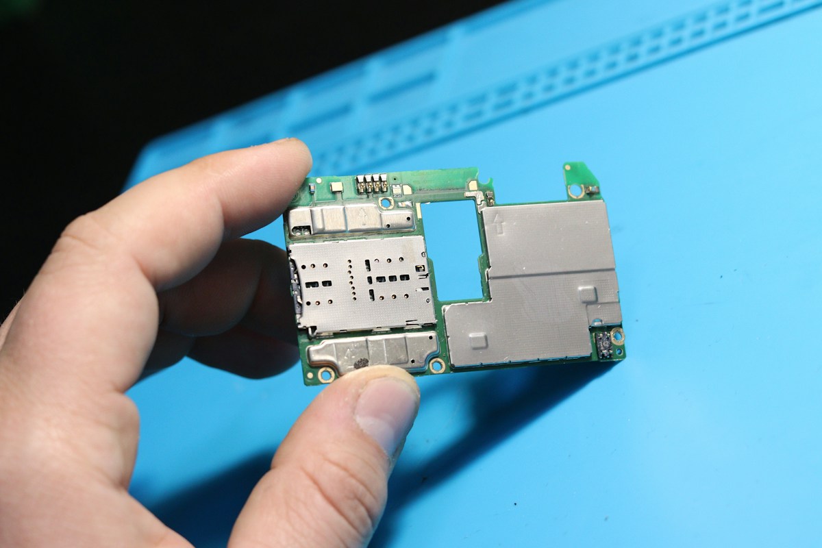 A hand holding a phone's SIM tray and circuit board