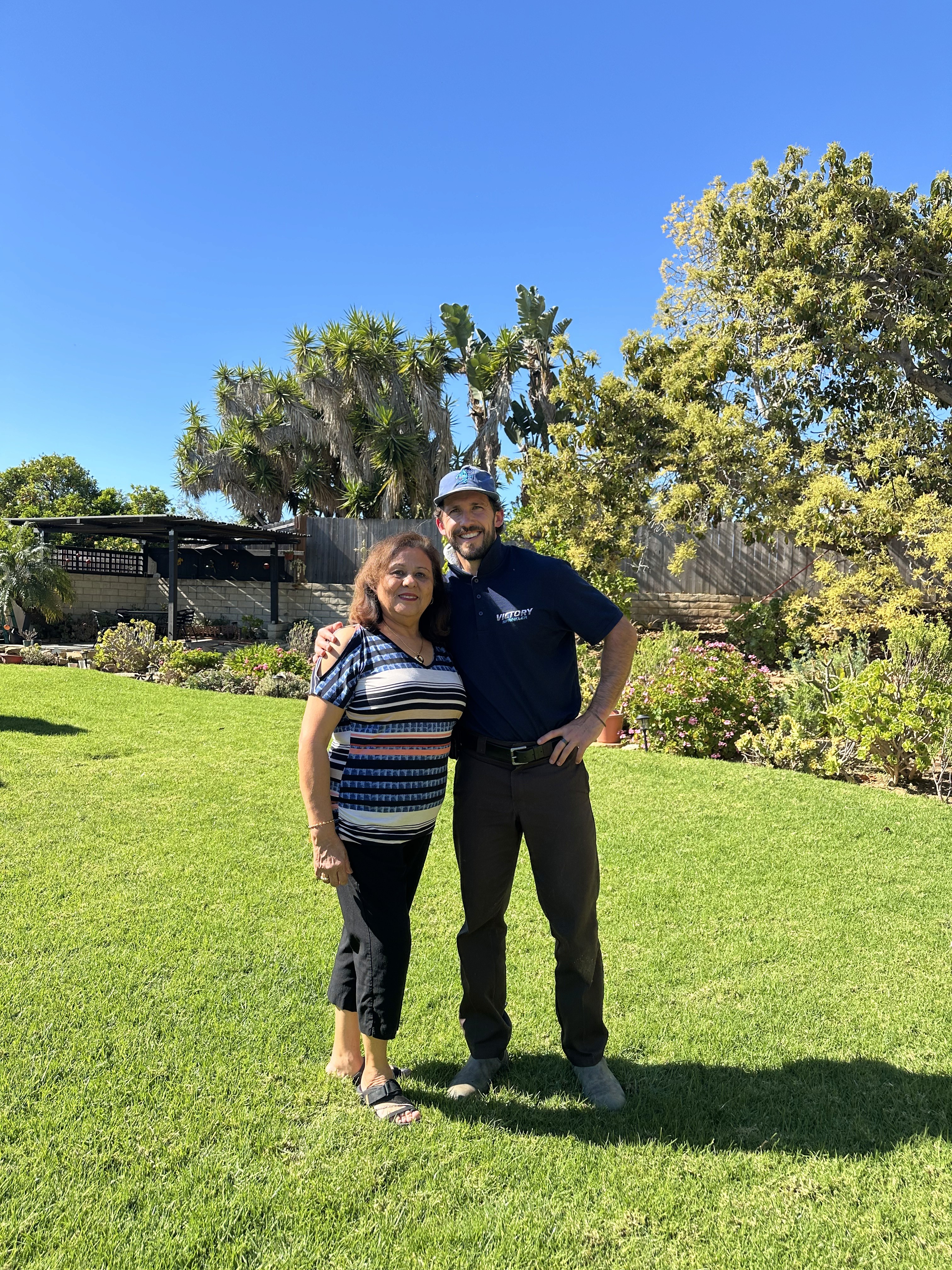 Owner Christian and customer Joe smiling in a front yard, representing a five-star service experience and successful sprinkler system repair.