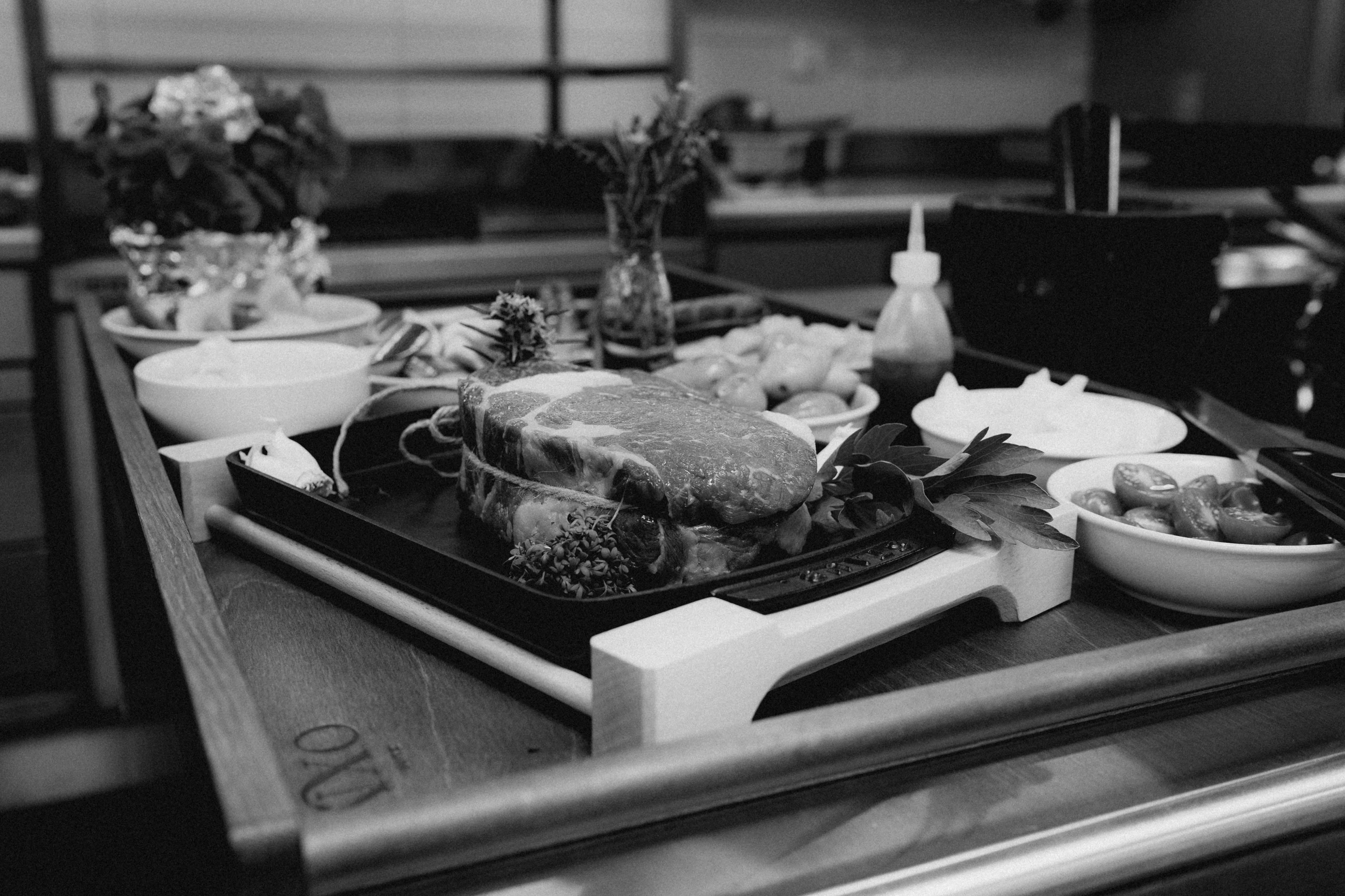 A black and white image showing a cluttered kitchen counter with various food items and utensils.
