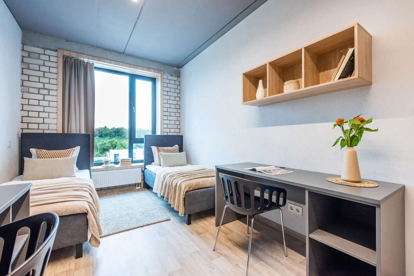 Furnished twin studio in Vilnius student accommodation with two beds, study desks and large window.