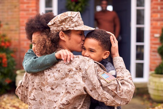 a woman in a military uniform hugging a little girl