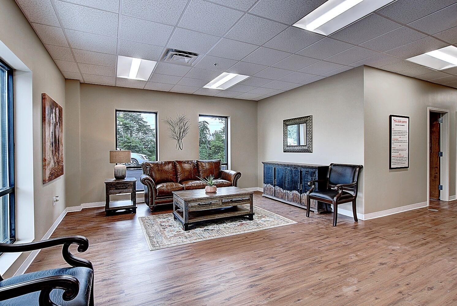 A spacious, modern waiting room with a comfortable sofa, coffee table, and large windows allowing natural light.
