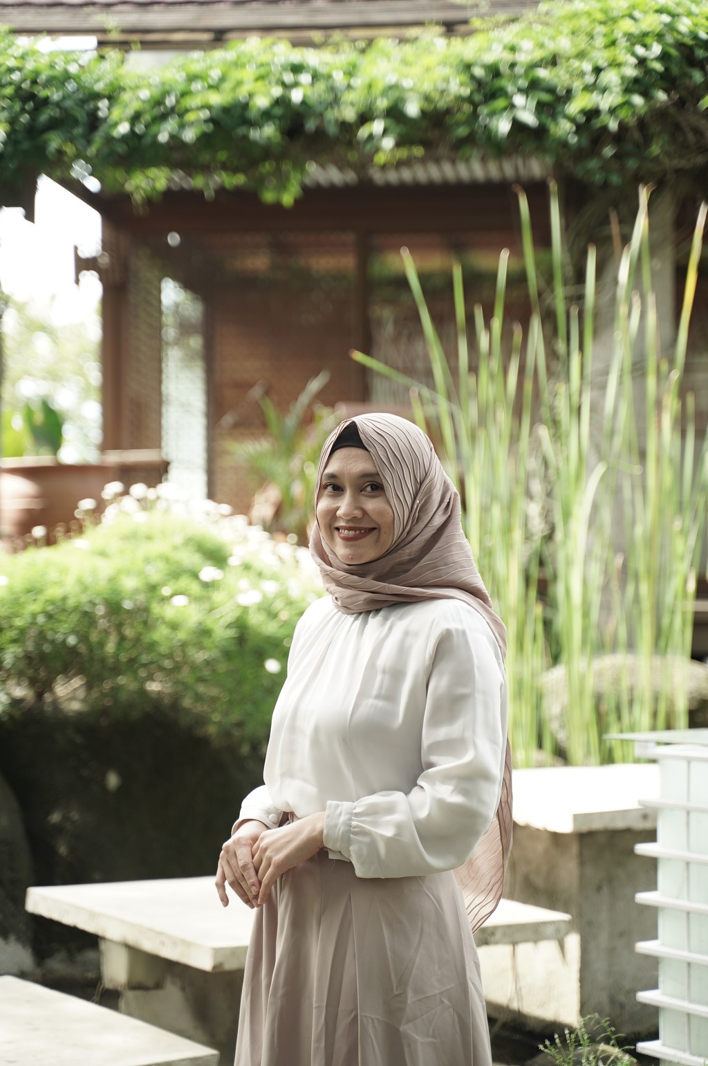 A winding road cuts through rocky terrain, surrounded by patches of green grass and illuminated by sunlight.