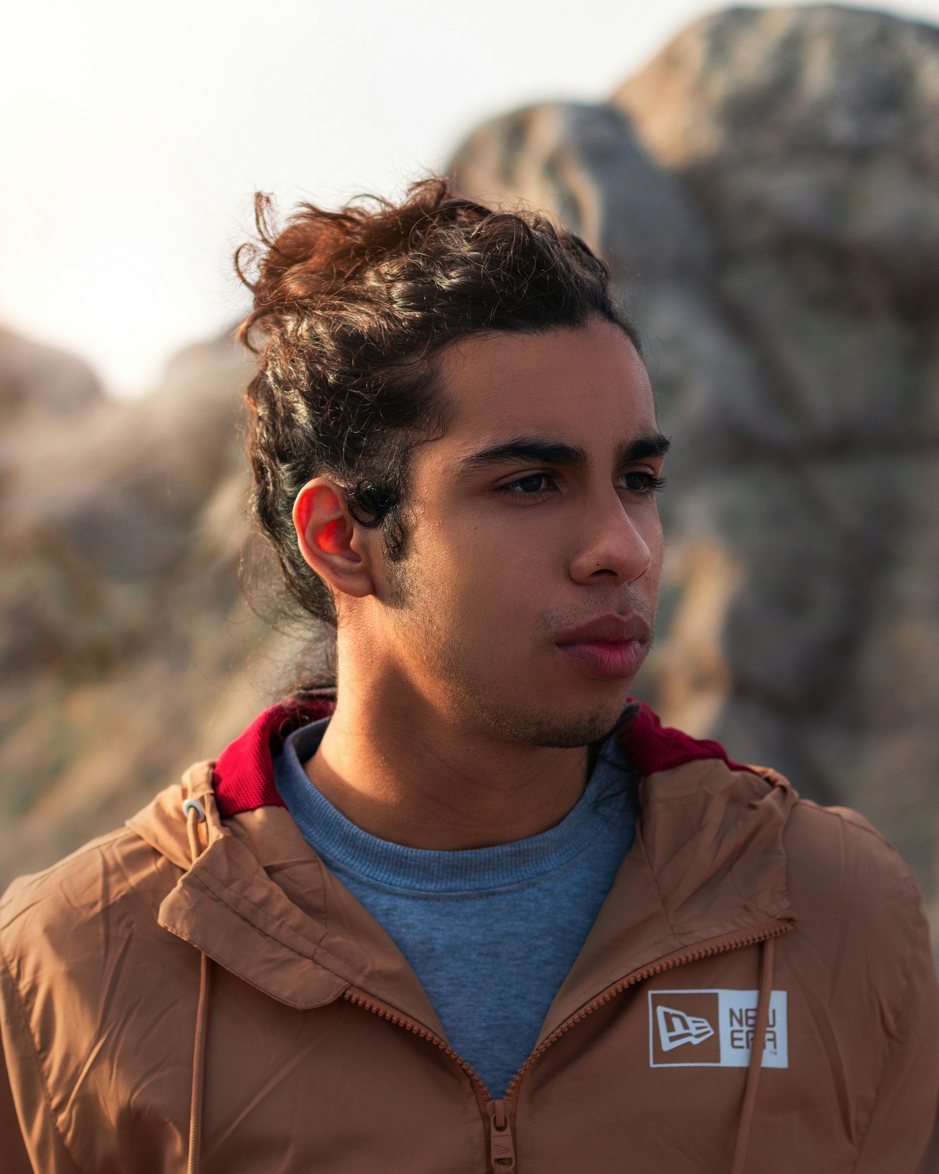 man in brown jacket with red and blue crew neck shirt