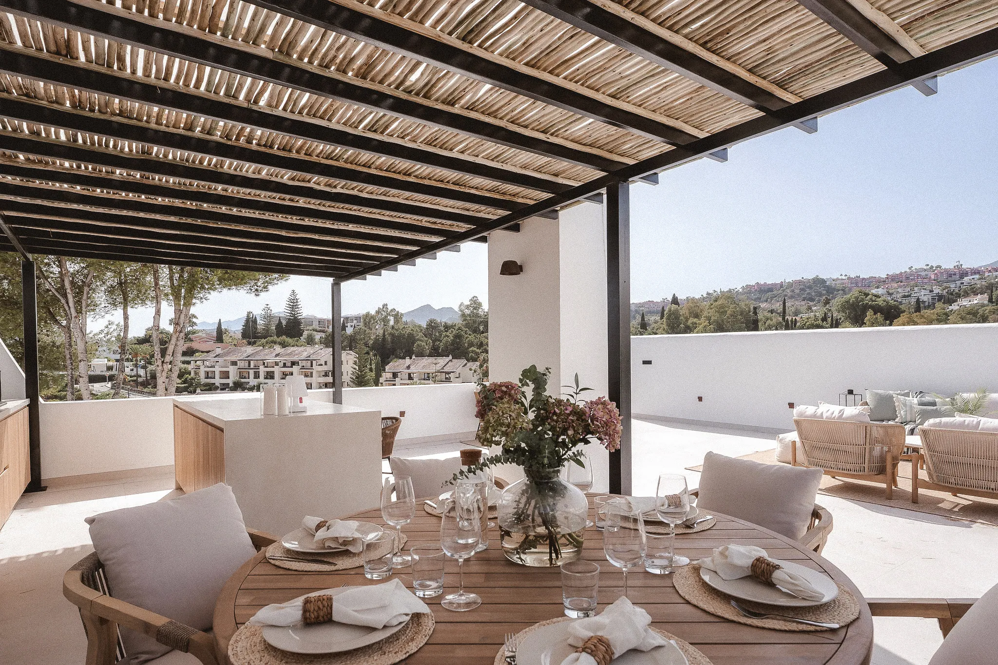 Outdoor dining terrace overlooking the Mediterranean with shaded pergola and contemporary furnishings.